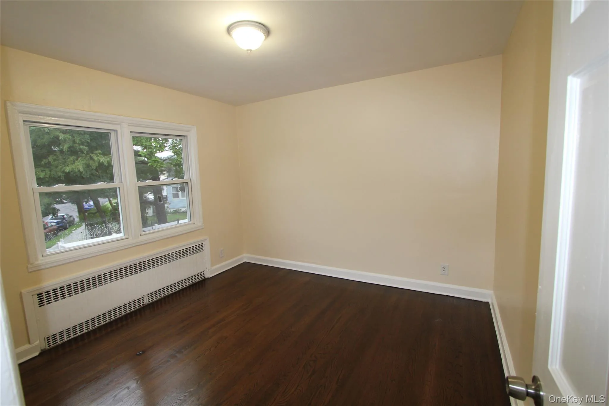 Empty room featuring radiator and dark wood-style floors Empty room featuring radiator and dark wood-style floors