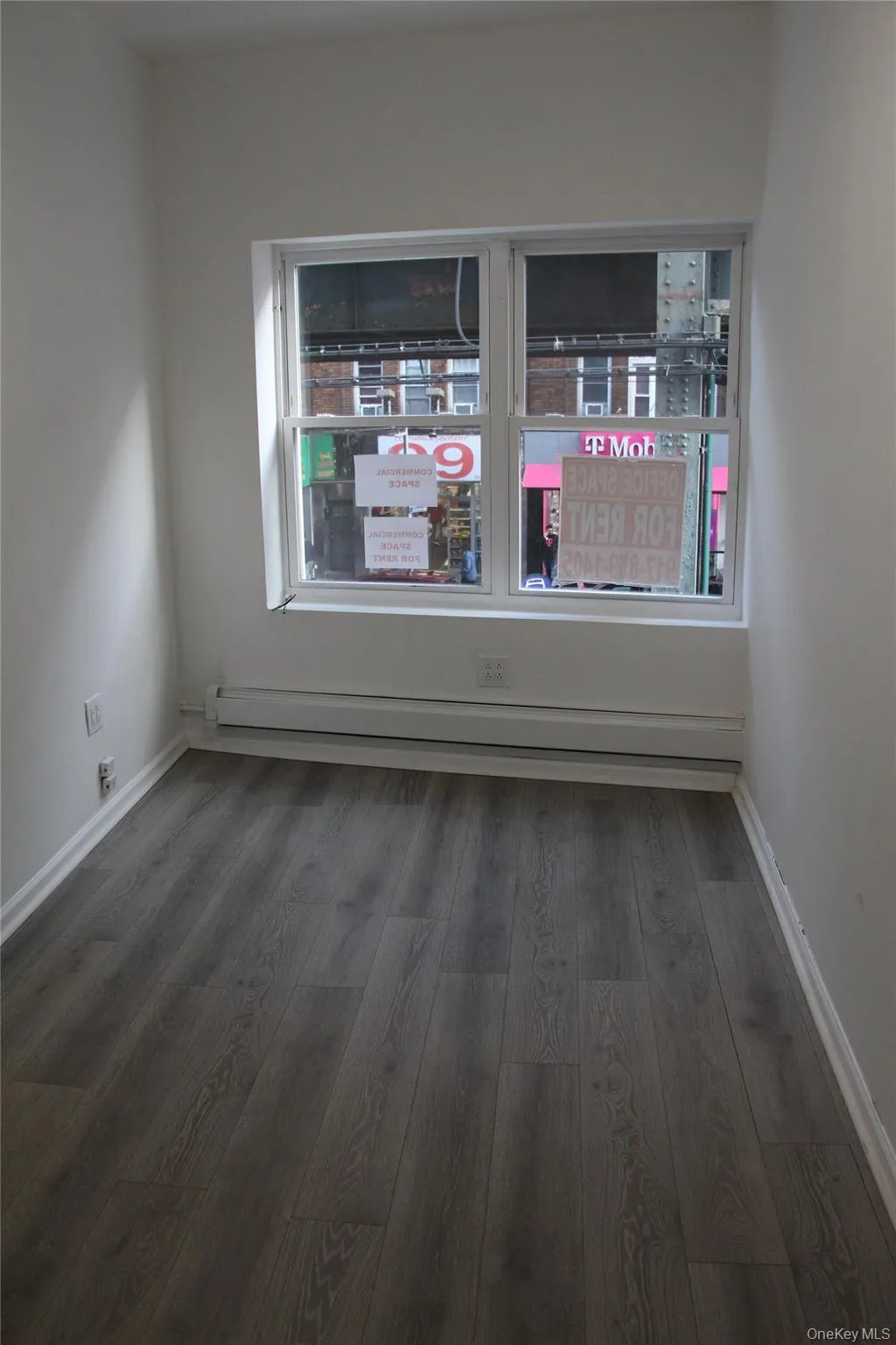 Unfurnished room with dark wood finished floors and a baseboard radiator Unfurnished room with dark wood finished floors and a baseboard radiator