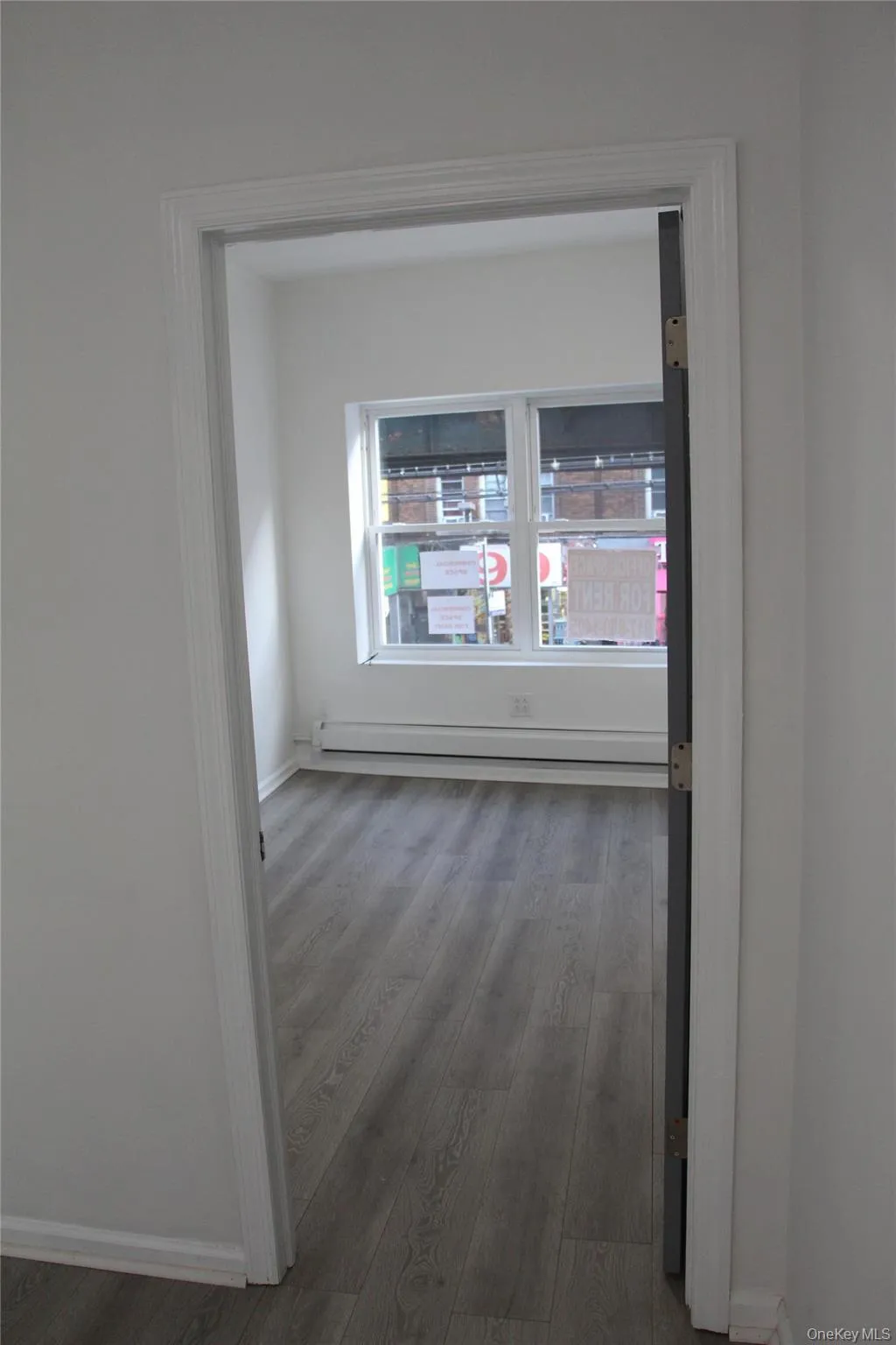 Unfurnished room with wood finished floors and a baseboard heating unit Unfurnished room with wood finished floors and a baseboard heating unit