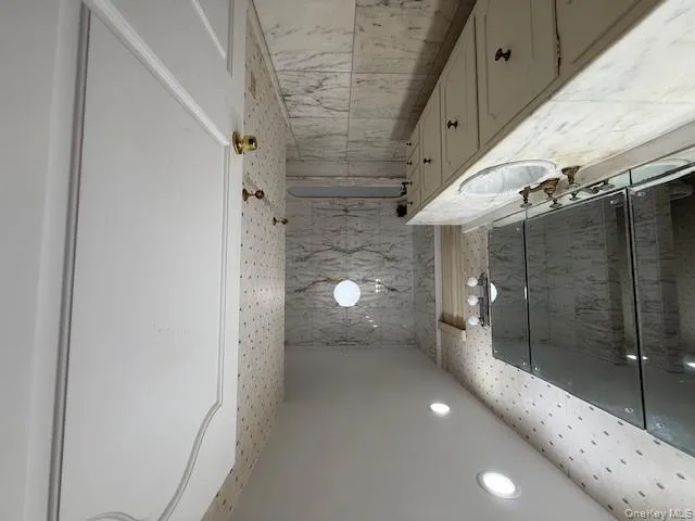 Bathroom with light marble finish flooring, vanity, a marble finish shower, recessed lighting, and tile walls Bathroom with light marble finish flooring, vanity, a marble finish shower, recessed lighting, and tile walls