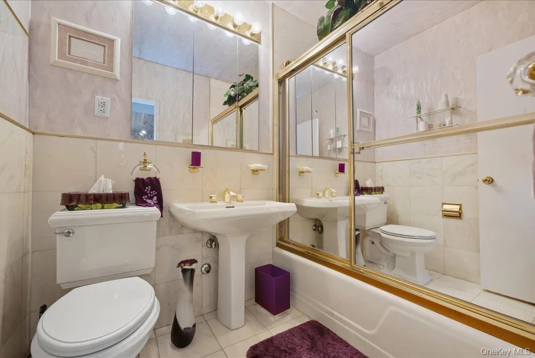 Bathroom featuring tile walls, tile patterned floors, and shower / washtub combination Bathroom featuring tile walls, tile patterned floors, and shower / washtub combination