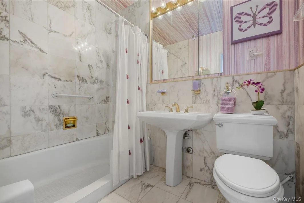 Bathroom featuring shower / bath combo with shower curtain and tile walls Bathroom featuring shower / bath combo with shower curtain and tile walls