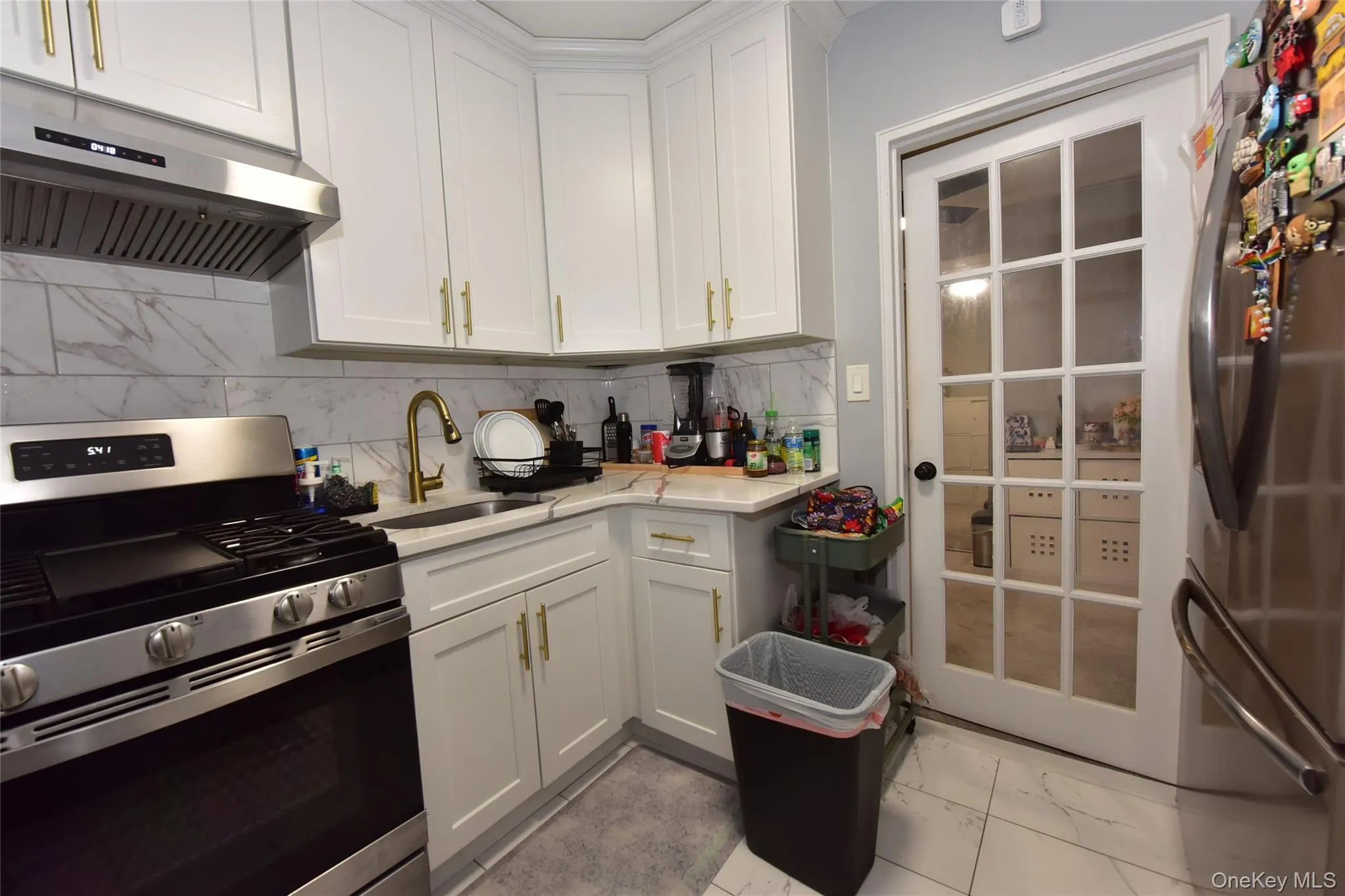 Kitchen featuring stainless steel appliances, white cabinets, and under cabinet range hood Kitchen featuring stainless steel appliances, white cabinets, and under cabinet range hood
