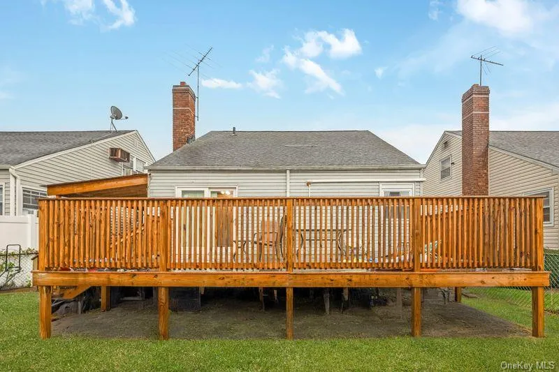 Back of house with a wooden deck, roof with shingles, and a chimney Back of house with a wooden deck, roof with shingles, and a chimney