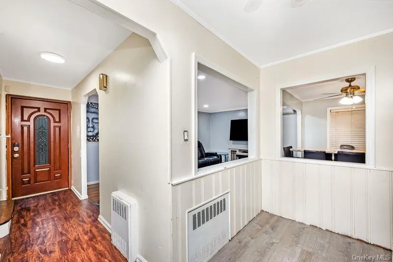 Entrance foyer featuring arched walkways, ceiling fan, dark wood-style floors, radiator, and ornamental molding Entrance foyer featuring arched walkways, ceiling fan, dark wood-style floors, radiator, and ornamental molding