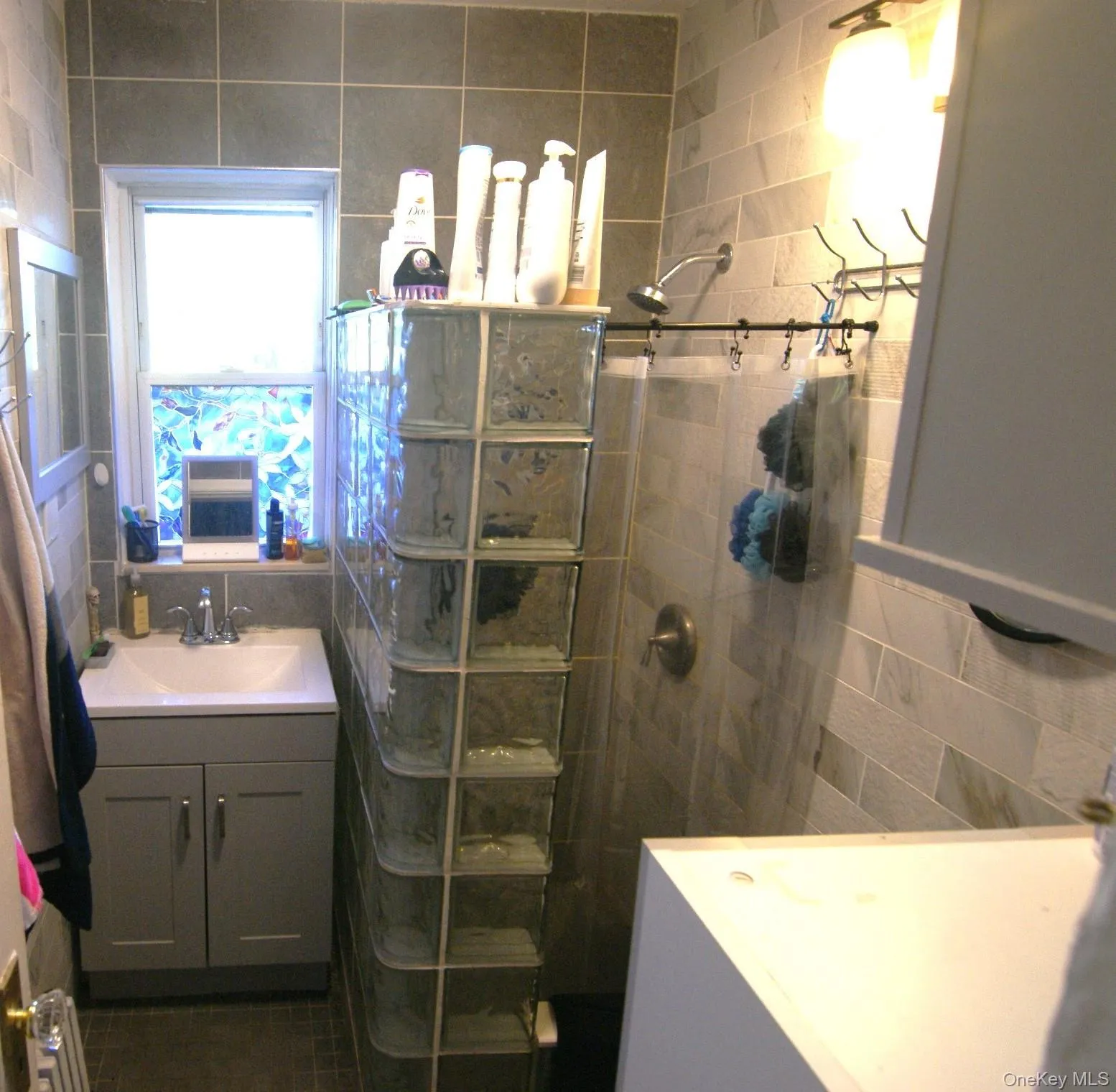 Full bath featuring vanity, tile walls, a walk in shower, and decorative backsplash Full bath featuring vanity, tile walls, a walk in shower, and decorative backsplash