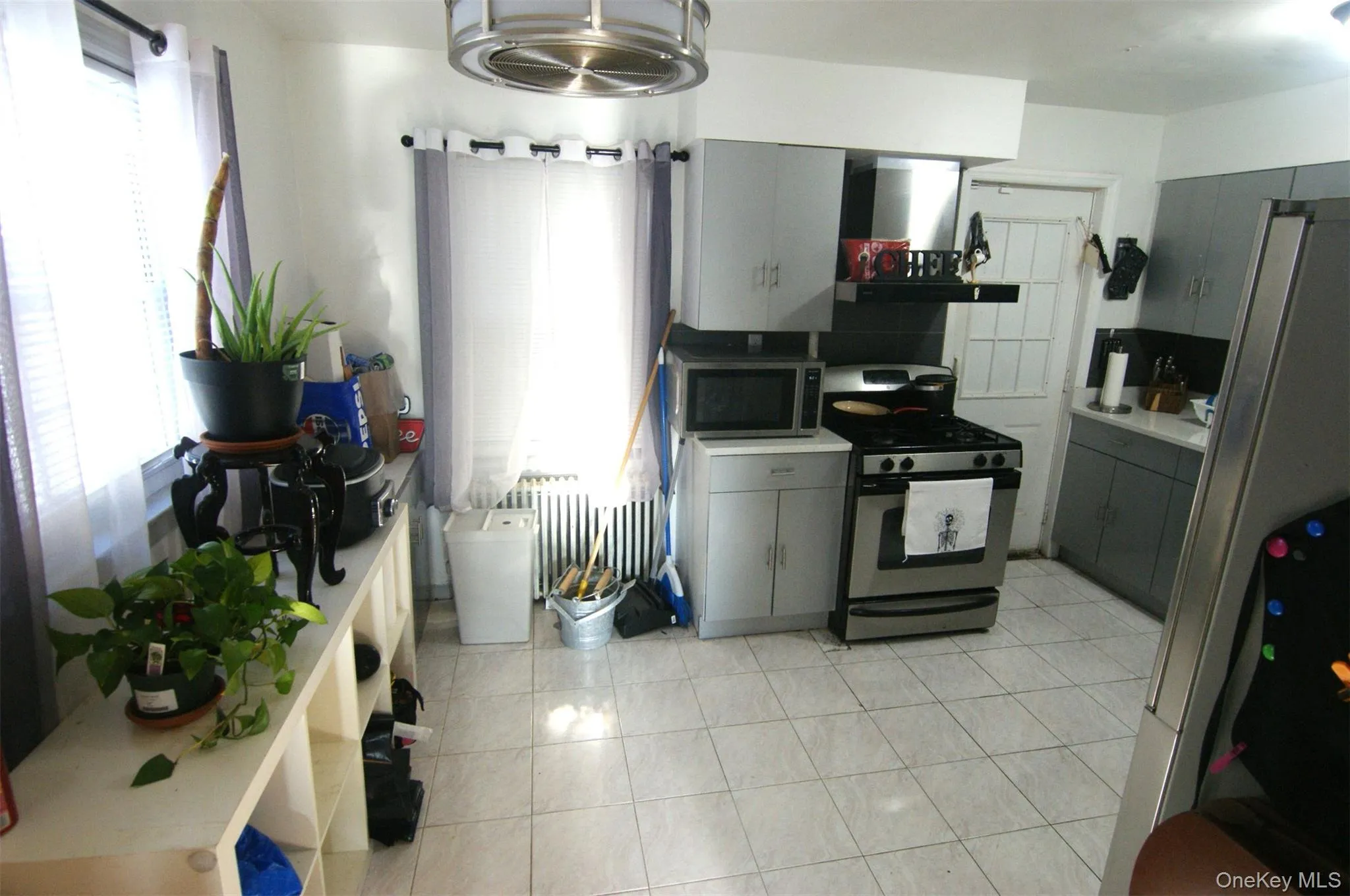 Kitchen with gray cabinets, stainless steel appliances, light countertops, and ventilation hood Kitchen with gray cabinets, stainless steel appliances, light countertops, and ventilation hood