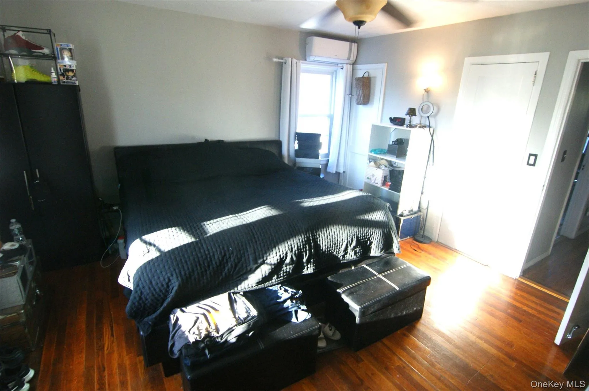 Bedroom featuring wood finished floors, a wall unit AC, and a ceiling fan Bedroom featuring wood finished floors, a wall unit AC, and a ceiling fan