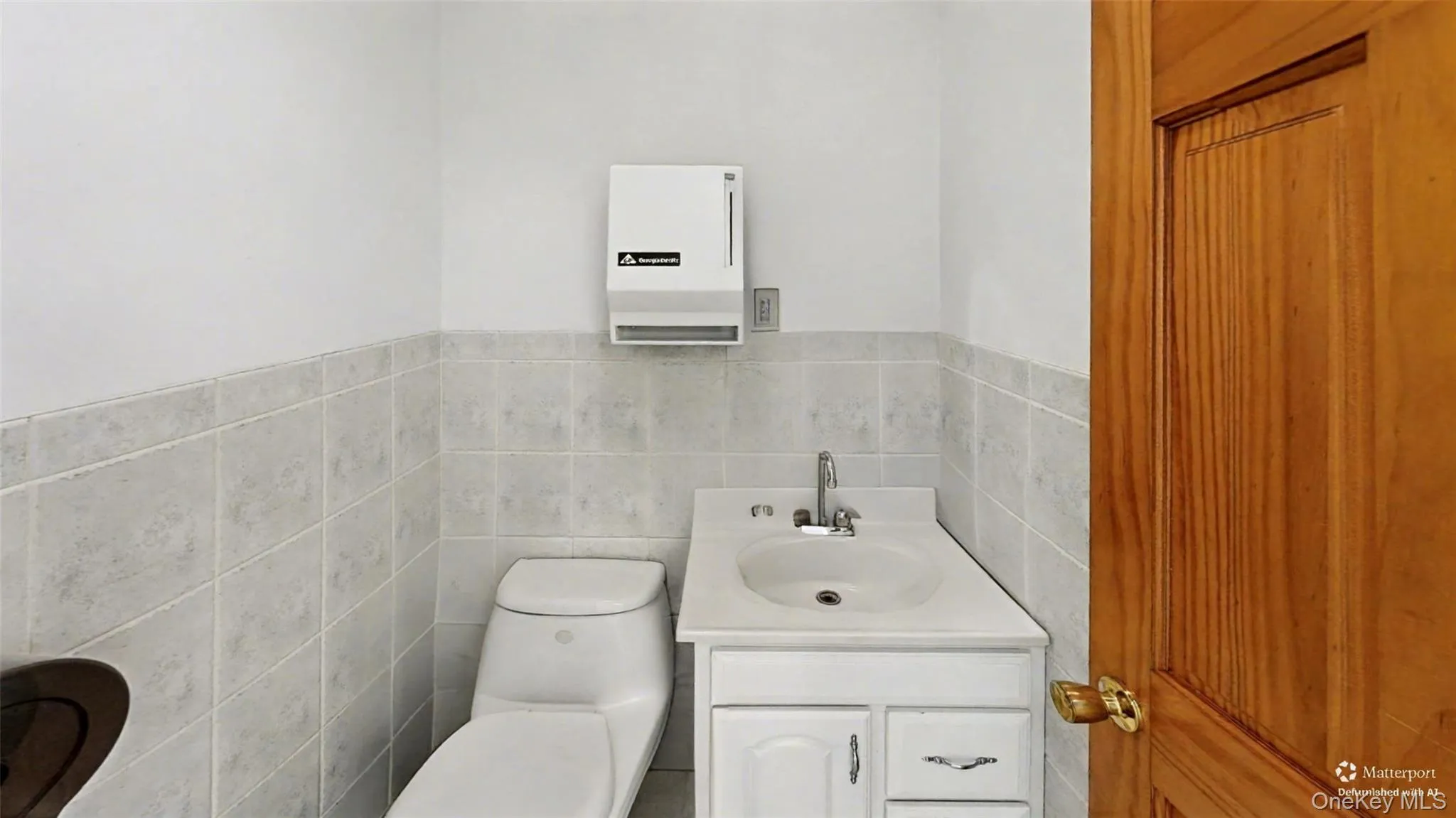 Half bathroom with vanity, tile walls, and wainscoting Half bathroom with vanity, tile walls, and wainscoting