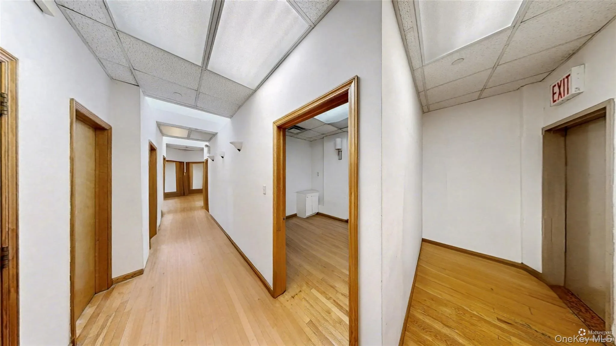 Hall with light wood-type flooring, elevator, and a drop ceiling Hall with light wood-type flooring, elevator, and a drop ceiling