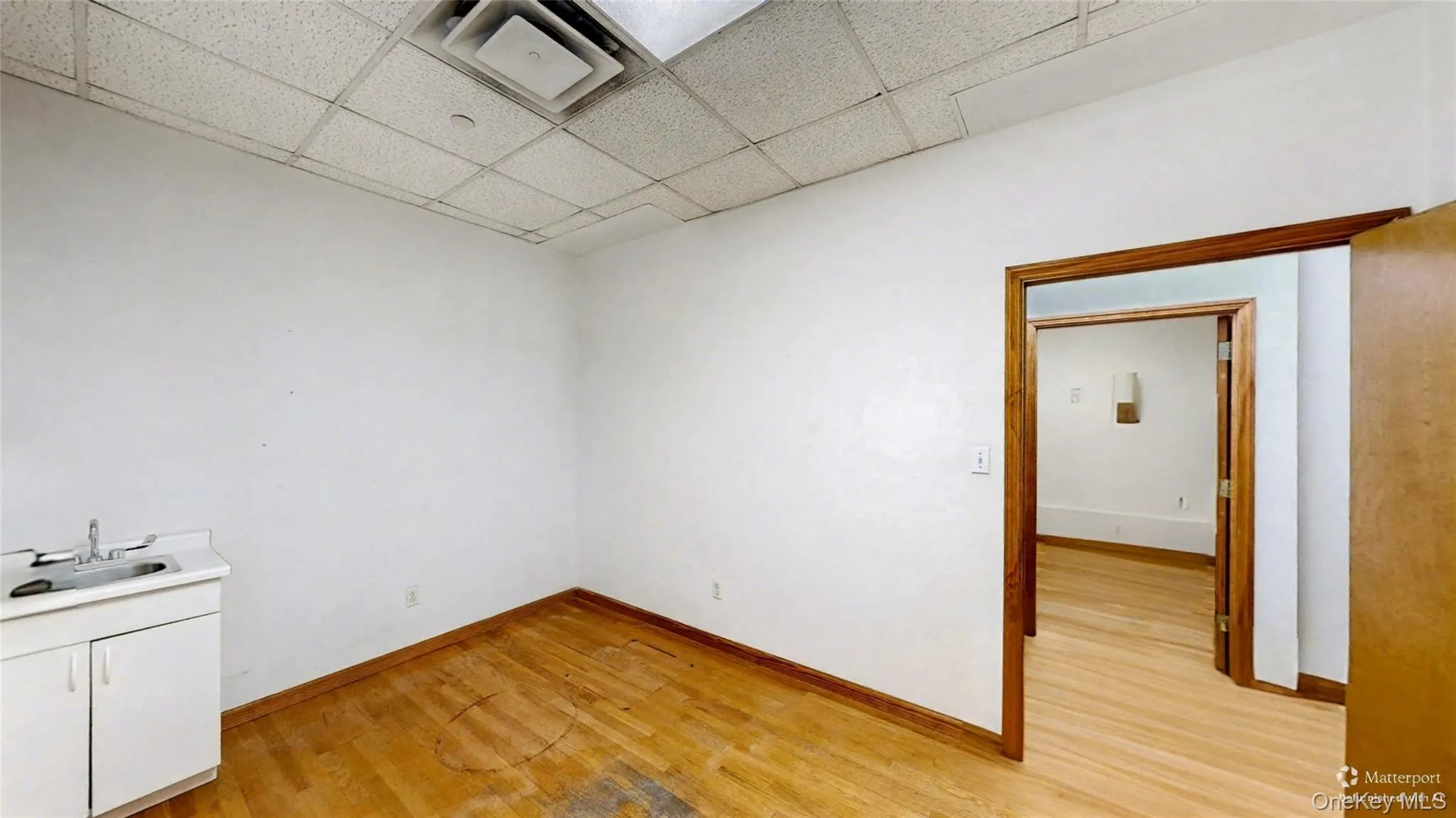 Unfurnished room with light wood-style flooring and a drop ceiling Unfurnished room with light wood-style flooring and a drop ceiling