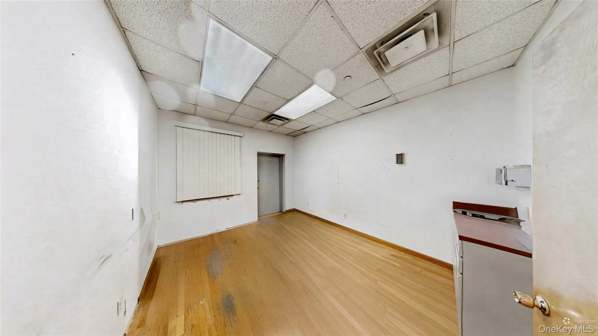Unfurnished room with light wood-style flooring and a drop ceiling Unfurnished room with light wood-style flooring and a drop ceiling