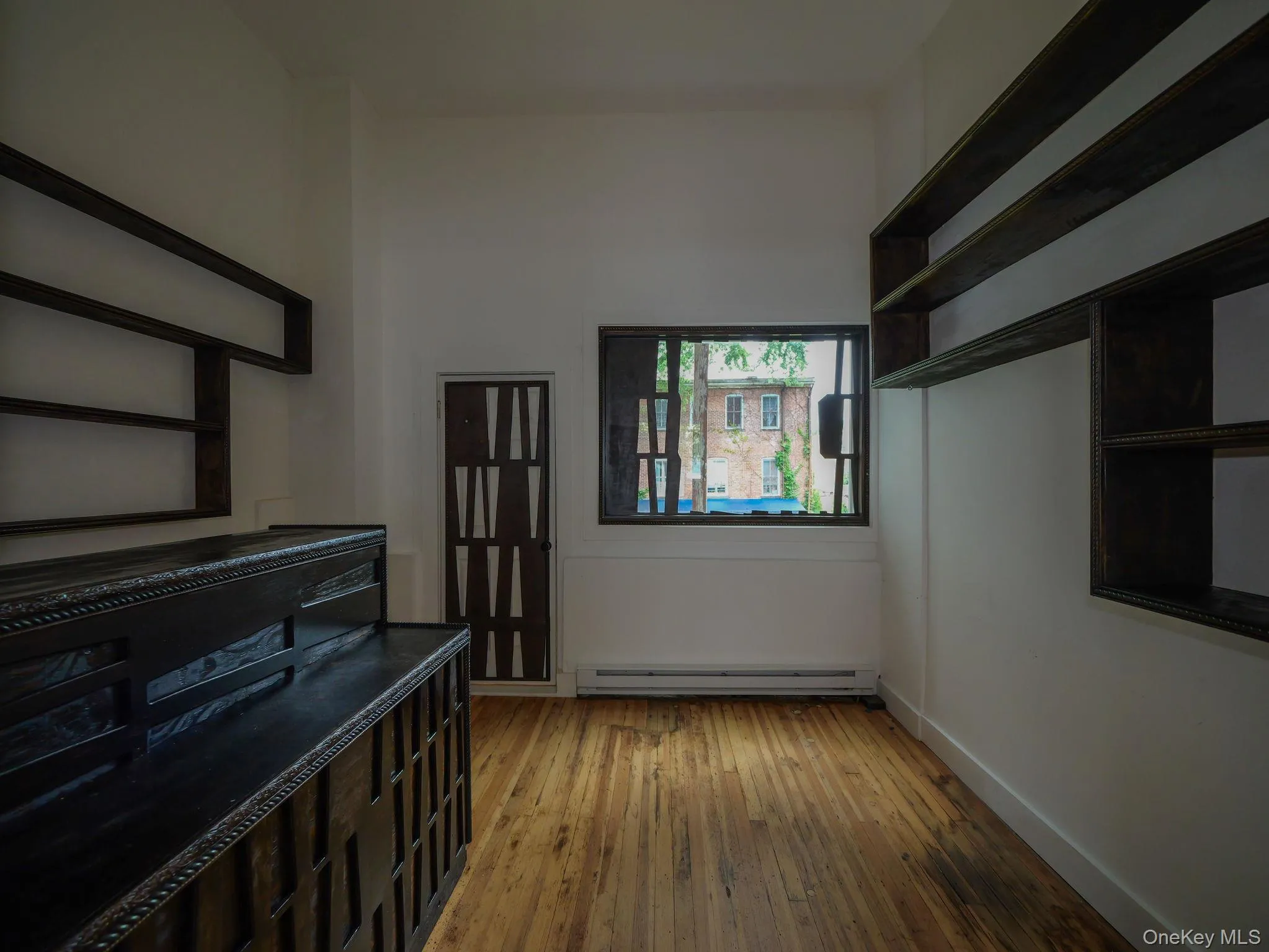 Corridor featuring light wood-style flooring and a baseboard heating unit Corridor featuring light wood-style flooring and a baseboard heating unit
