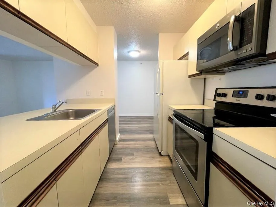 Kitchen featuring light countertops, light wood finished floors, and white cabinetry Kitchen featuring light countertops, light wood finished floors, and white cabinetry