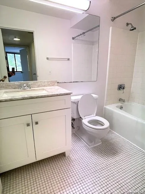 Full bathroom featuring shower combination, vanity, and light tile patterned floors Full bathroom featuring shower combination, vanity, and light tile patterned floors