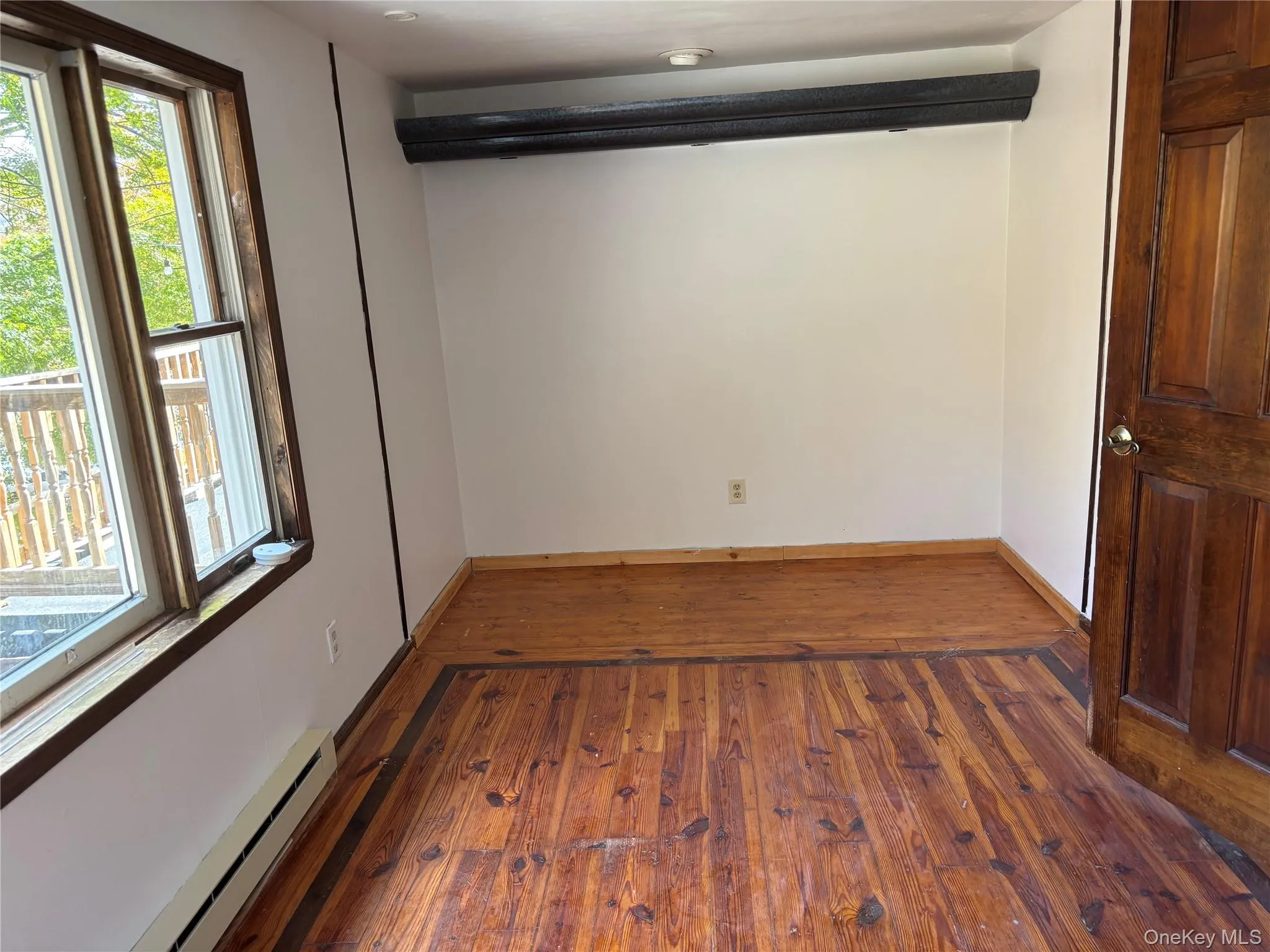 Spare room with a baseboard radiator and dark wood finished floors Spare room with a baseboard radiator and dark wood finished floors