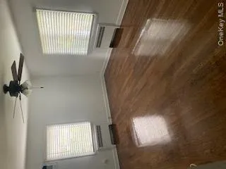 Unfurnished room featuring radiator heating unit, dark wood-type flooring, and a ceiling fan Unfurnished room featuring radiator heating unit, dark wood-type flooring, and a ceiling fan