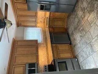 Kitchen with ceiling fan, brown cabinets, tasteful backsplash, refrigerator, and stove Kitchen with ceiling fan, brown cabinets, tasteful backsplash, refrigerator, and stove