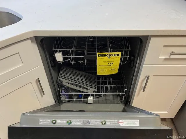 Kitchen view of dishwashing machine, light stone countertops, and white cabinetry Kitchen view of dishwashing machine, light stone countertops, and white cabinetry