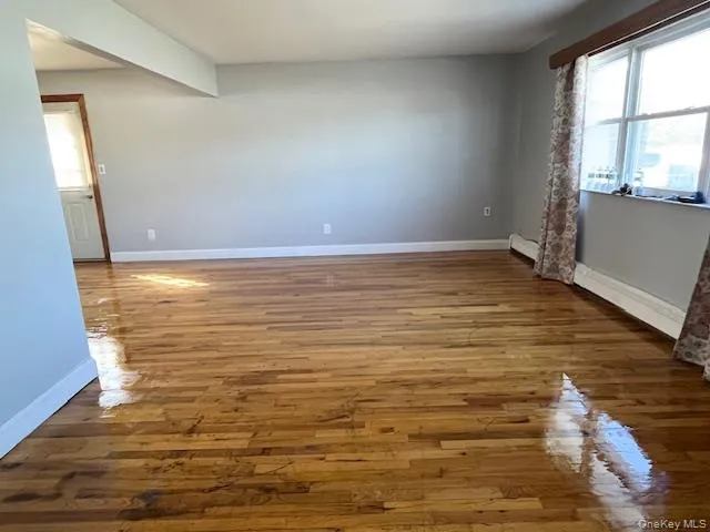 Spare room featuring light wood-type flooring and a baseboard heating unit Spare room featuring light wood-type flooring and a baseboard heating unit