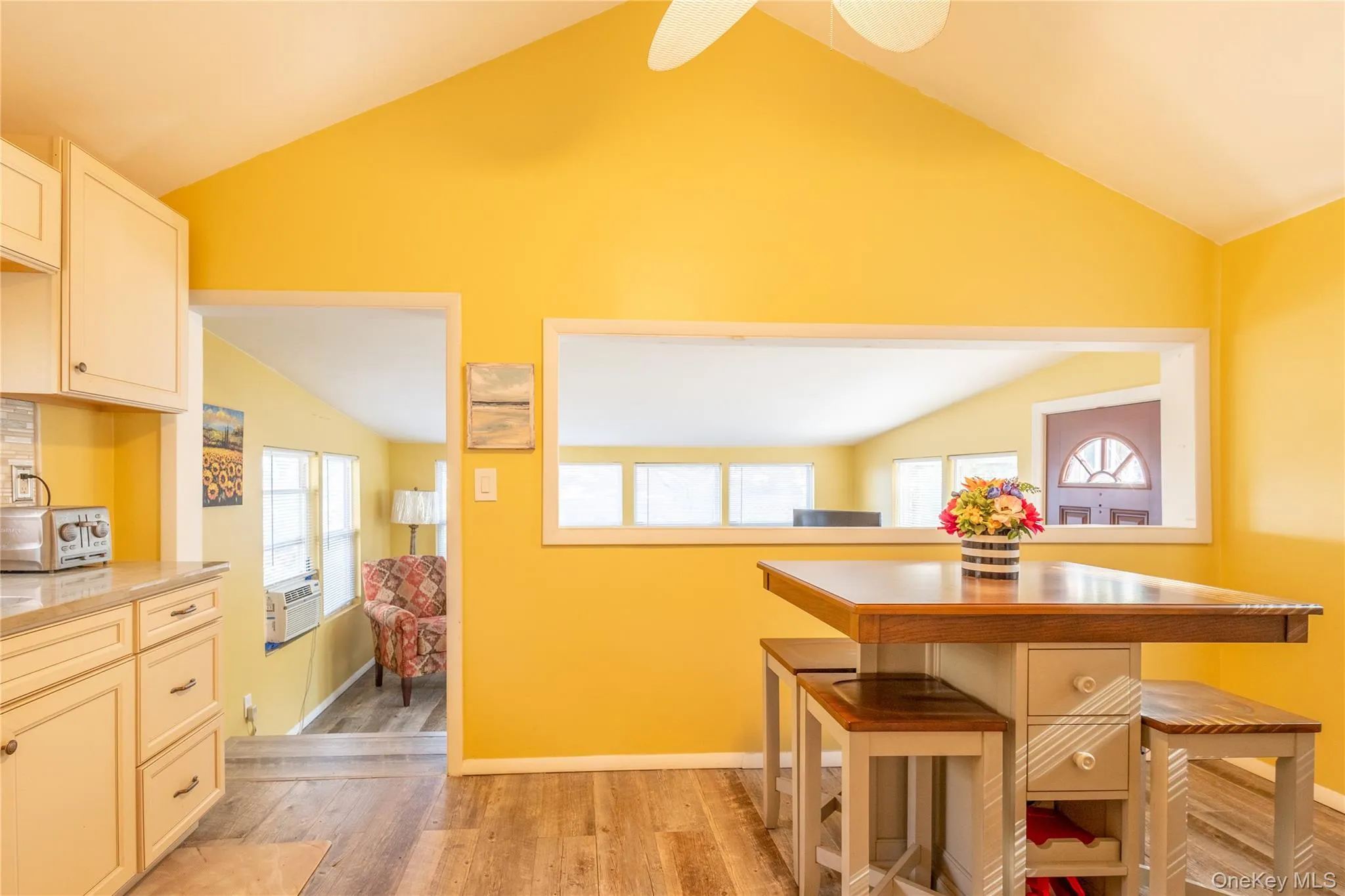 Kitchen with lofted ceiling, light wood-type flooring, light stone countertops, and white cabinets Kitchen with lofted ceiling, light wood-type flooring, light stone countertops, and white cabinets