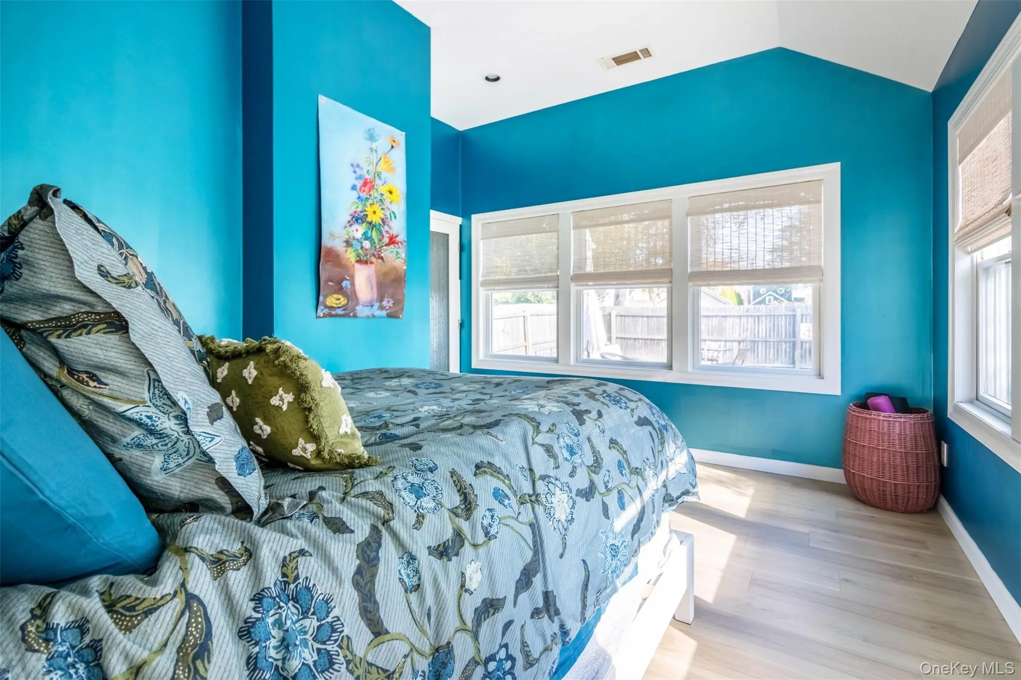 Bedroom featuring multiple windows, wood finished floors, and vaulted ceiling Bedroom featuring multiple windows, wood finished floors, and vaulted ceiling