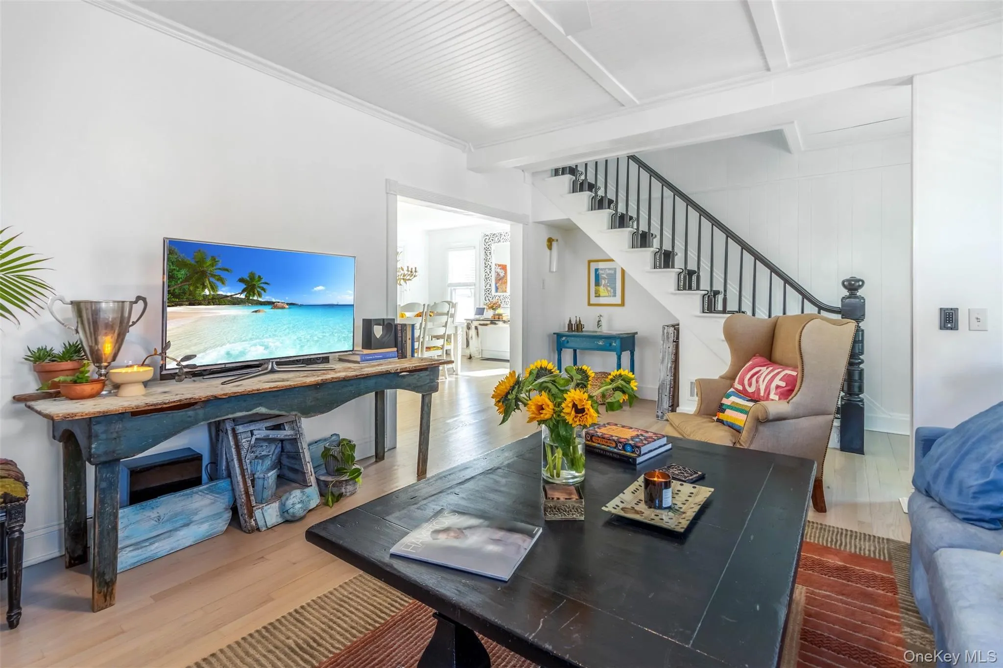 Living room with wood finished floors, stairs, and beamed ceiling Living room with wood finished floors, stairs, and beamed ceiling