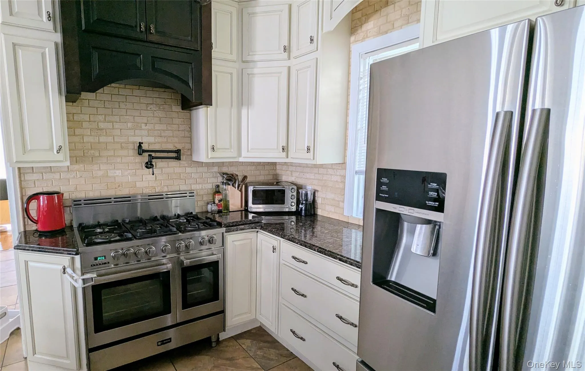 Kitchen featuring stainless steel appliances, white cabinetry, dark stone counters, and backsplash Kitchen featuring stainless steel appliances, white cabinetry, dark stone counters, and backsplash