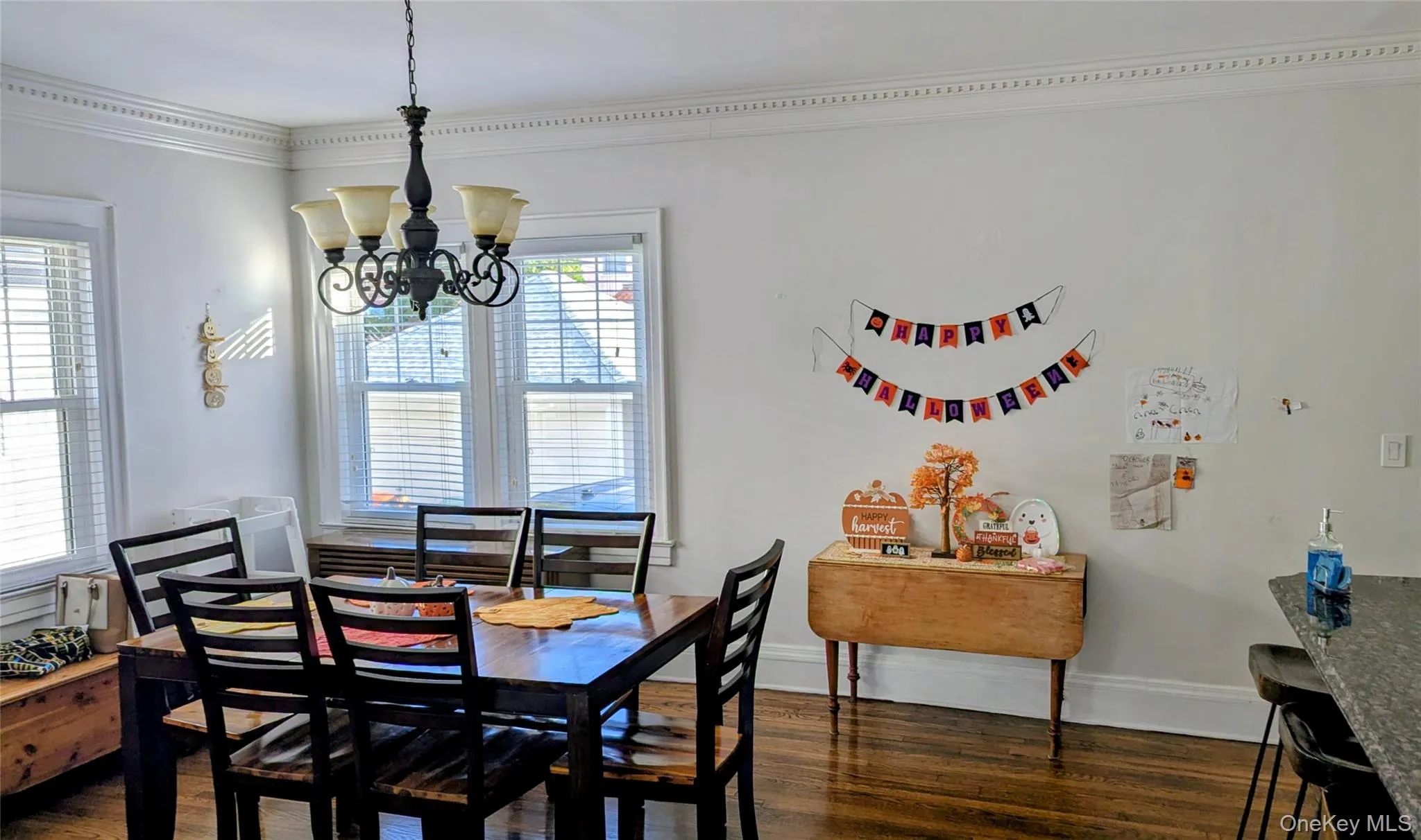 Dining room with ornamental molding, dark wood finished floors, and a chandelier Dining room with ornamental molding, dark wood finished floors, and a chandelier