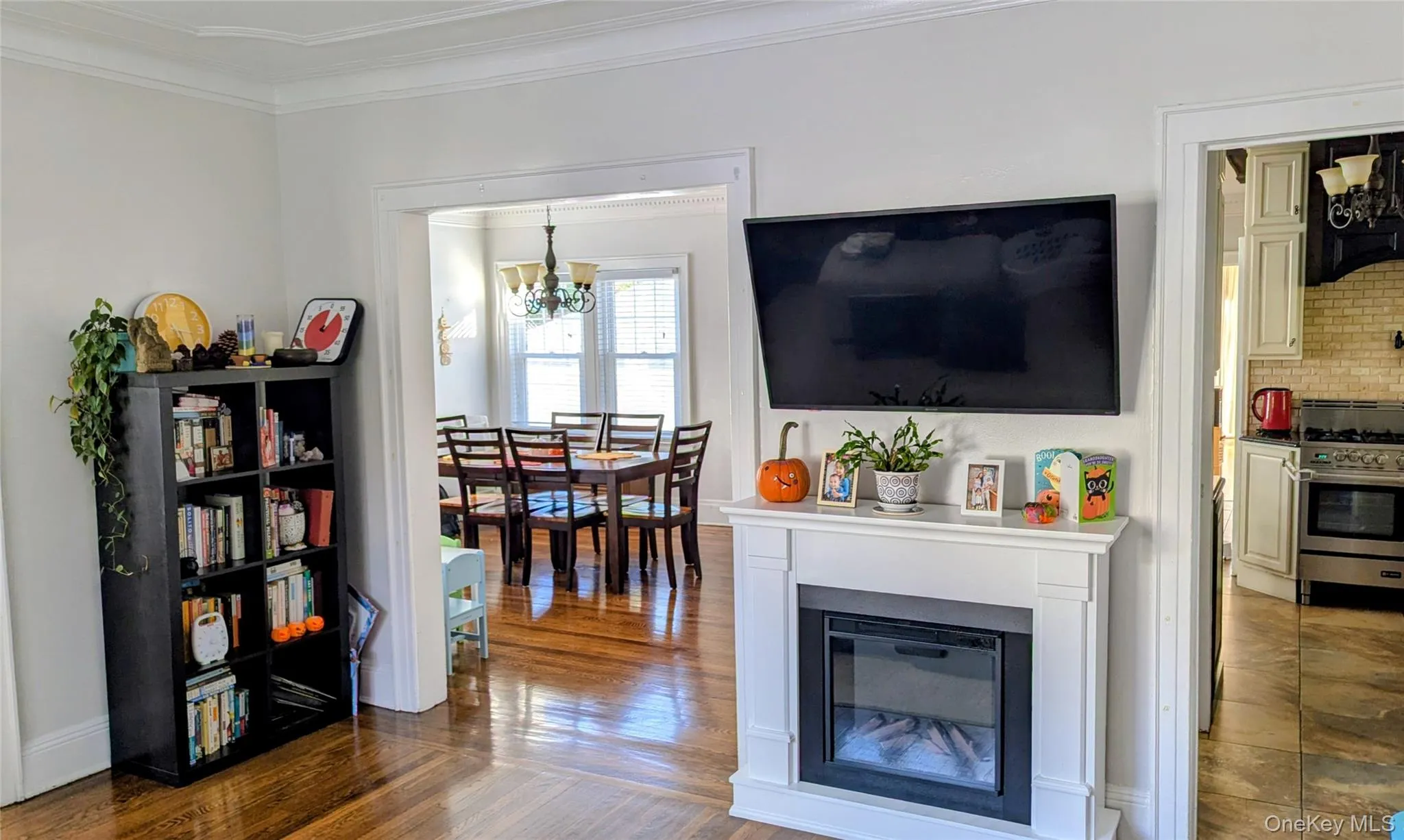Living room featuring ornamental molding, a glass covered fireplace, a chandelier, and dark wood-style floors Living room featuring ornamental molding, a glass covered fireplace, a chandelier, and dark wood-style floors