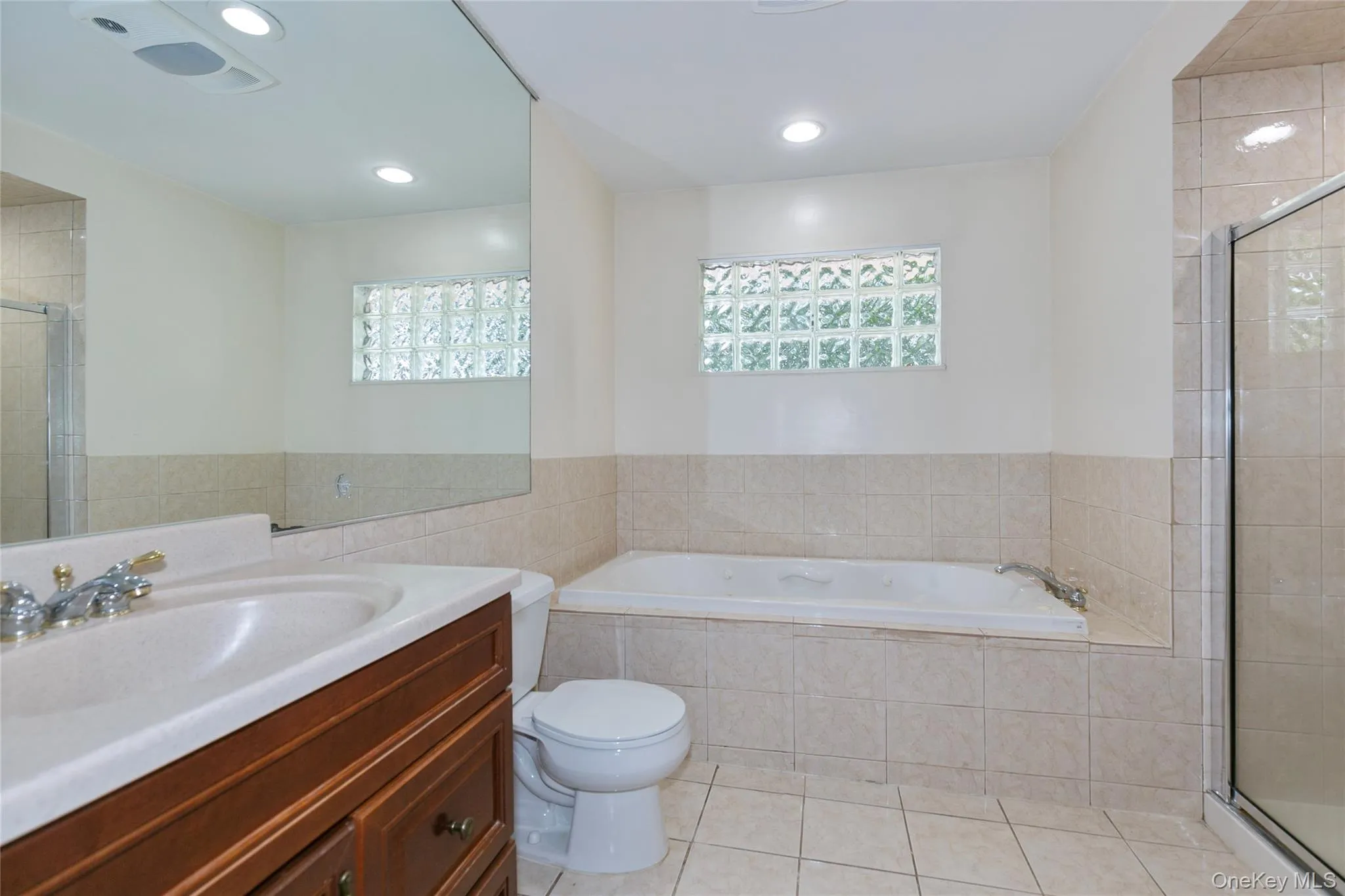 Full bath with a stall shower, vanity, light tile patterned floors, a bath, and recessed lighting Full bath with a stall shower, vanity, light tile patterned floors, a bath, and recessed lighting