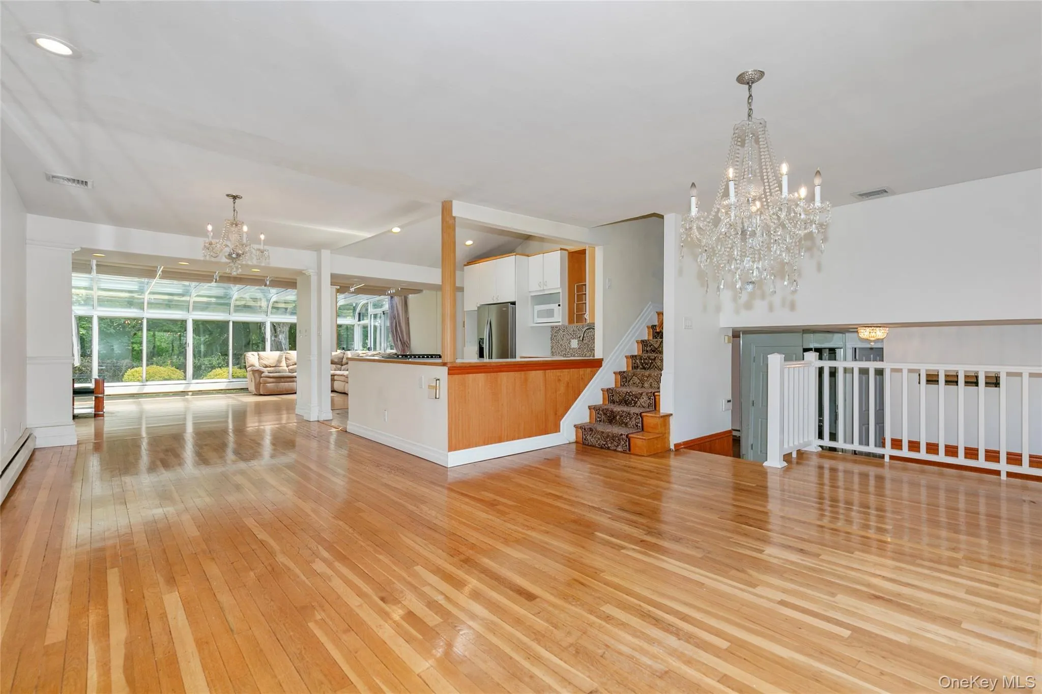 Unfurnished living room featuring a chandelier, light wood-type flooring, stairs, and recessed lighting Unfurnished living room featuring a chandelier, light wood-type flooring, stairs, and recessed lighting
