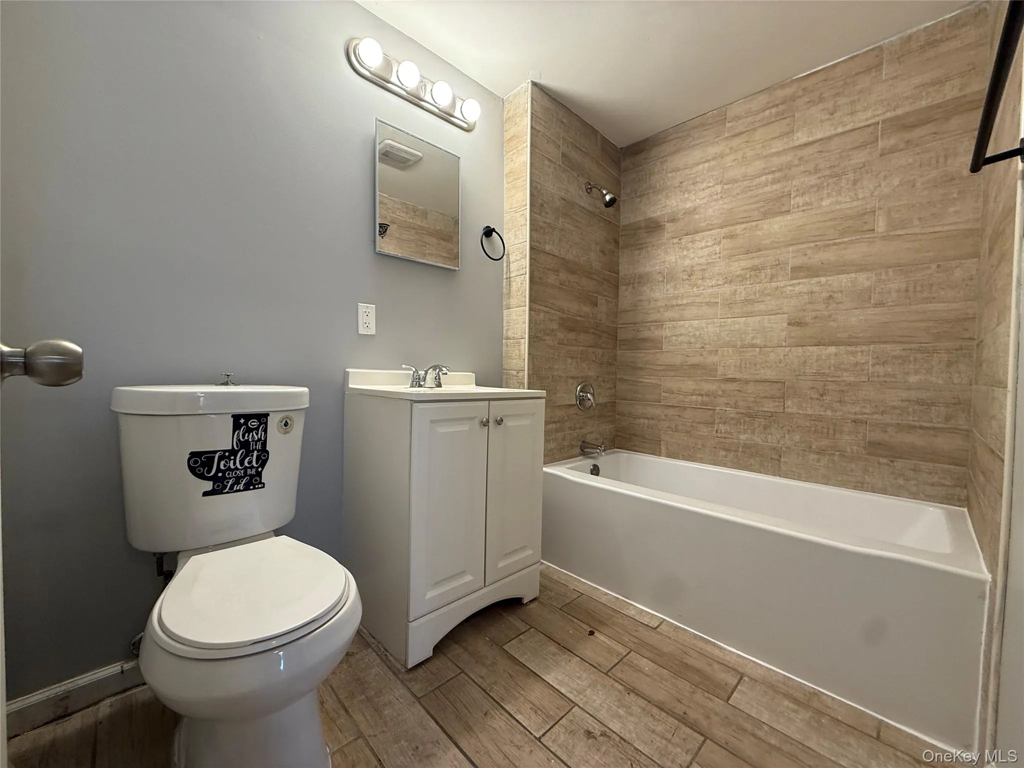 Full bathroom featuring wood finish floors, vanity, and bathtub / shower combination Full bathroom featuring wood finish floors, vanity, and bathtub / shower combination