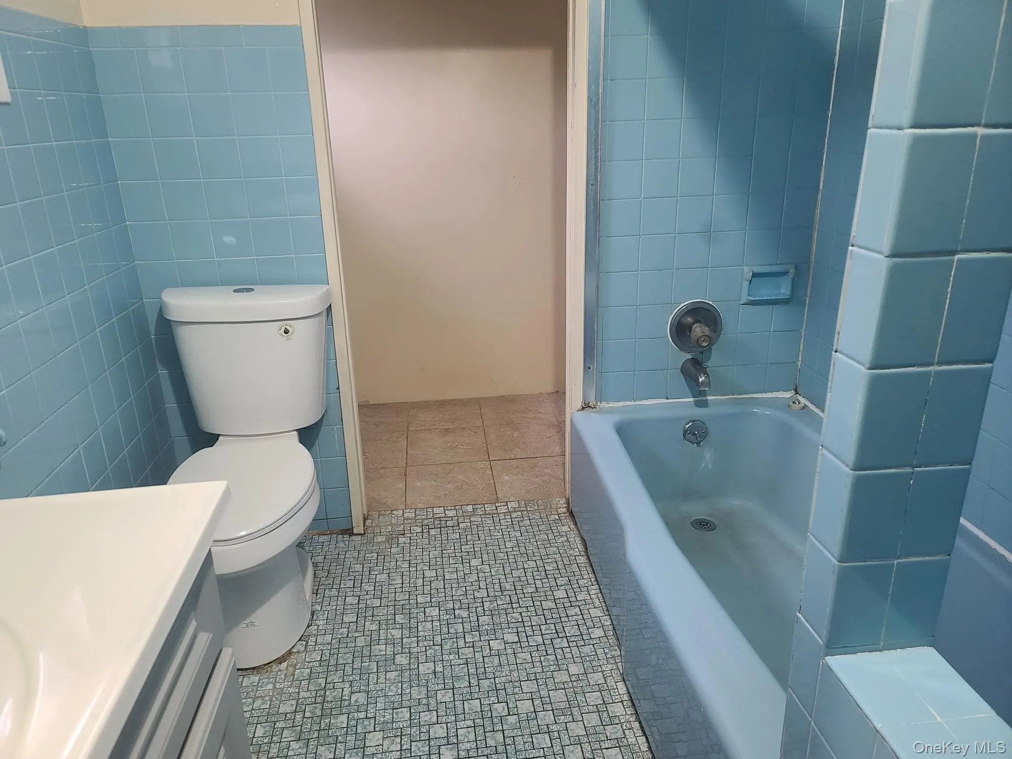 Full bathroom with vanity, a tub to relax in, tile walls, and tile patterned floors Full bathroom with vanity, a tub to relax in, tile walls, and tile patterned floors