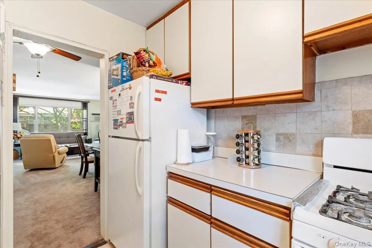 Kitchen with white appliances, light countertops, white cabinetry, light carpet, and brown cabinetry Kitchen with white appliances, light countertops, white cabinetry, light carpet, and brown cabinetry