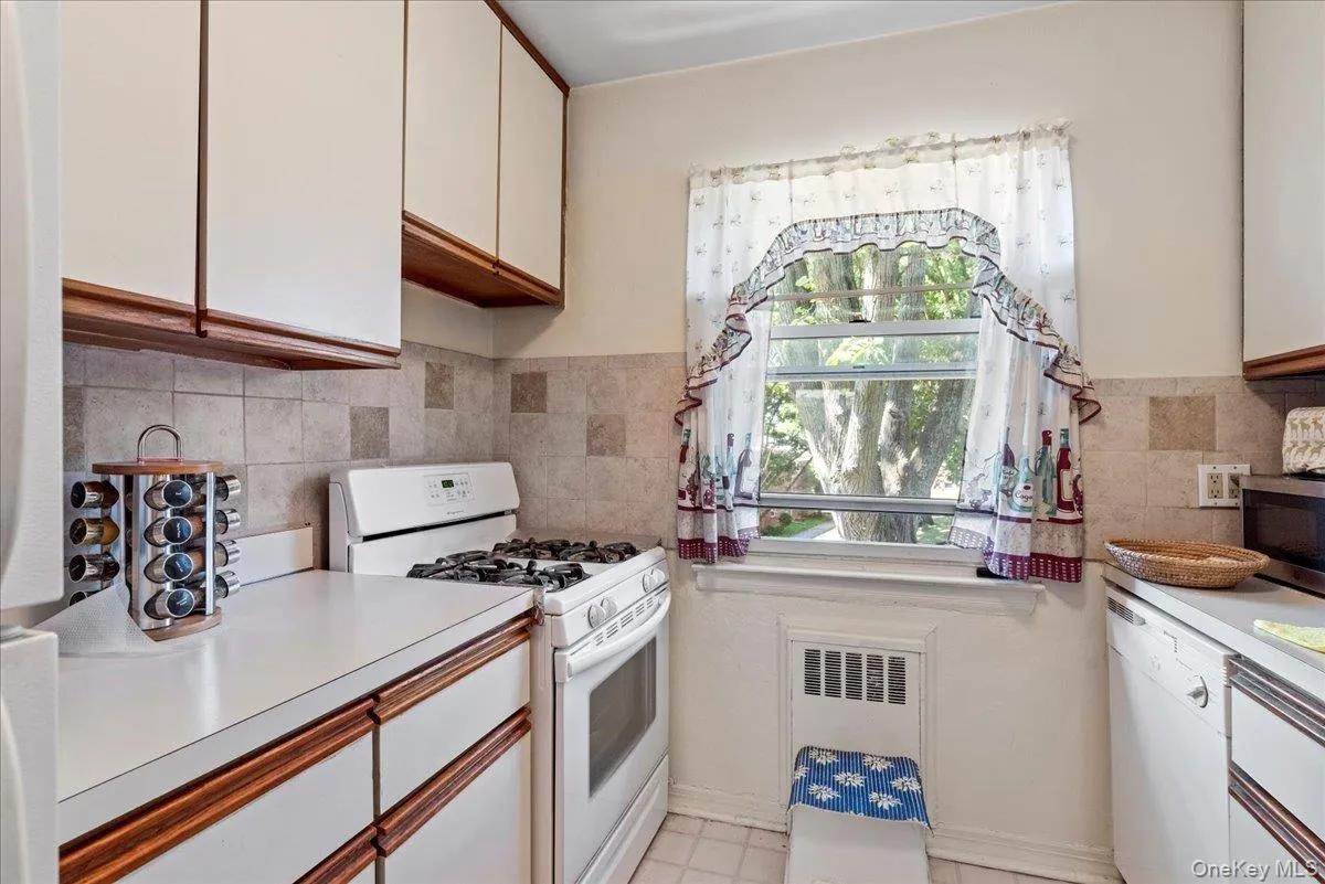 Kitchen with white appliances, white cabinets, light countertops, and brown cabinetry Kitchen with white appliances, white cabinets, light countertops, and brown cabinetry
