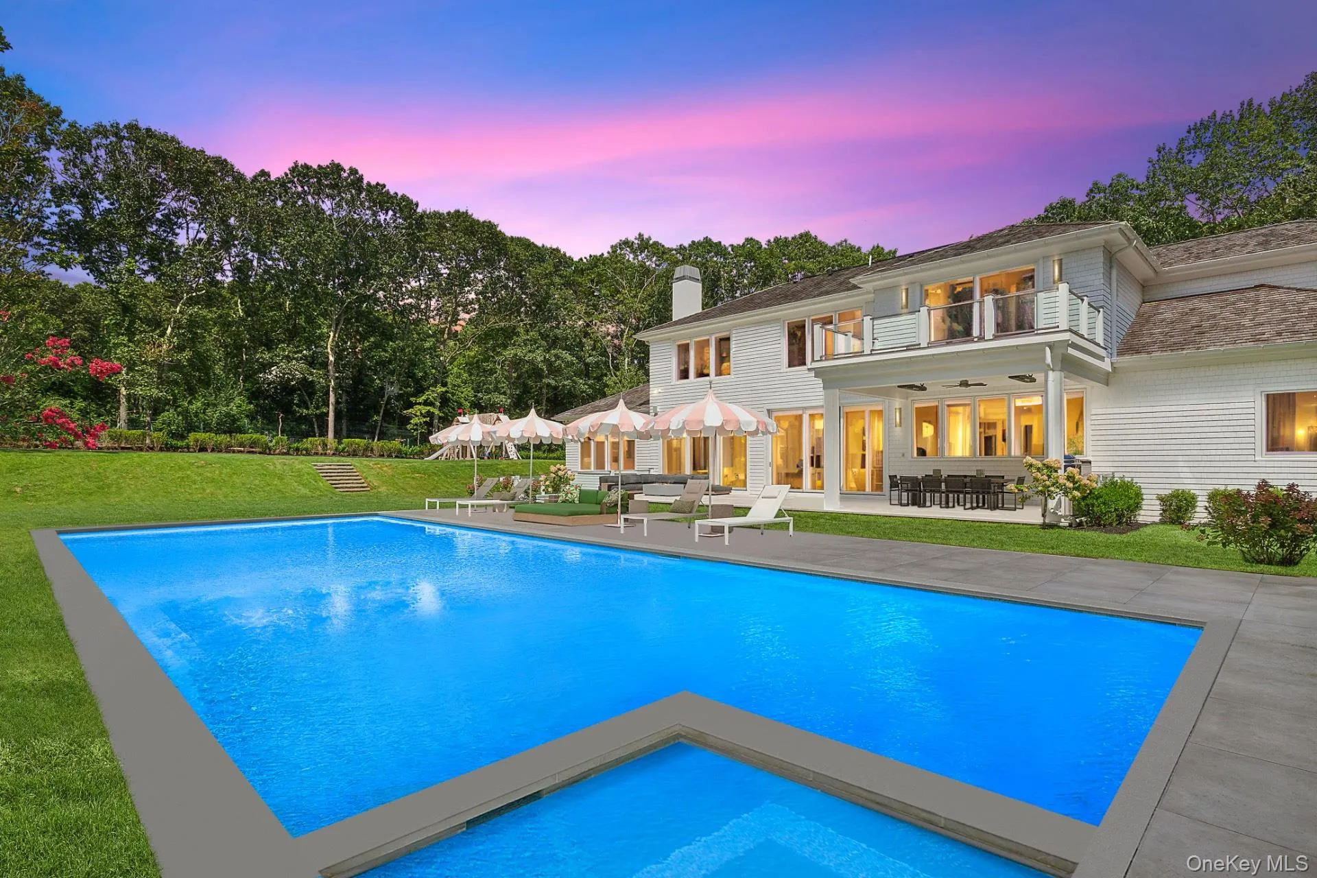 Pool at dusk with a patio area, a lawn, a balcony, an outdoor pool, and a ceiling fan Pool at dusk with a patio area, a lawn, a balcony, an outdoor pool, and a ceiling fan