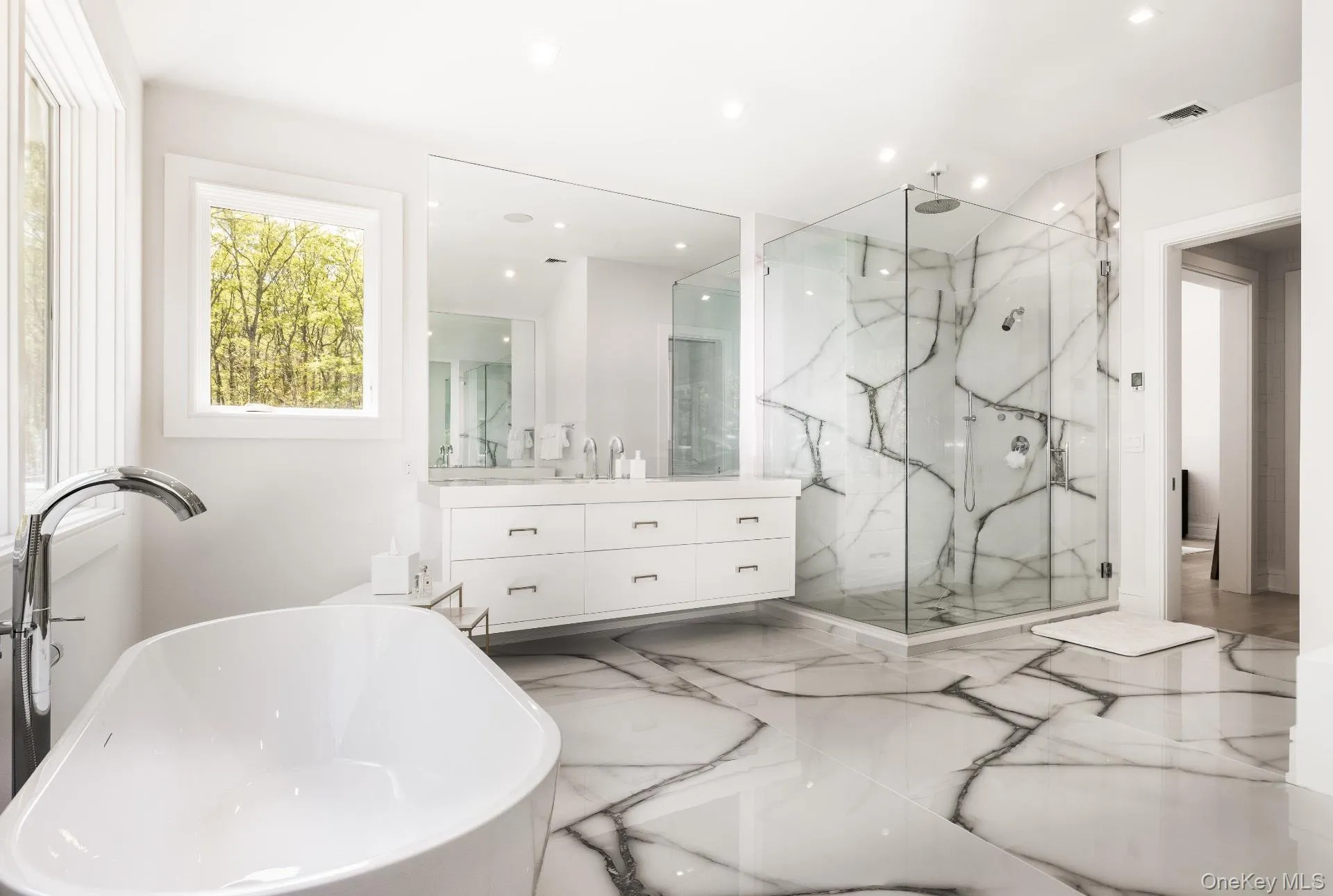 Bathroom featuring vanity, marble tiled floors, a soaking tub, a marble finish shower, and recessed lighting Bathroom featuring vanity, marble tiled floors, a soaking tub, a marble finish shower, and recessed lighting