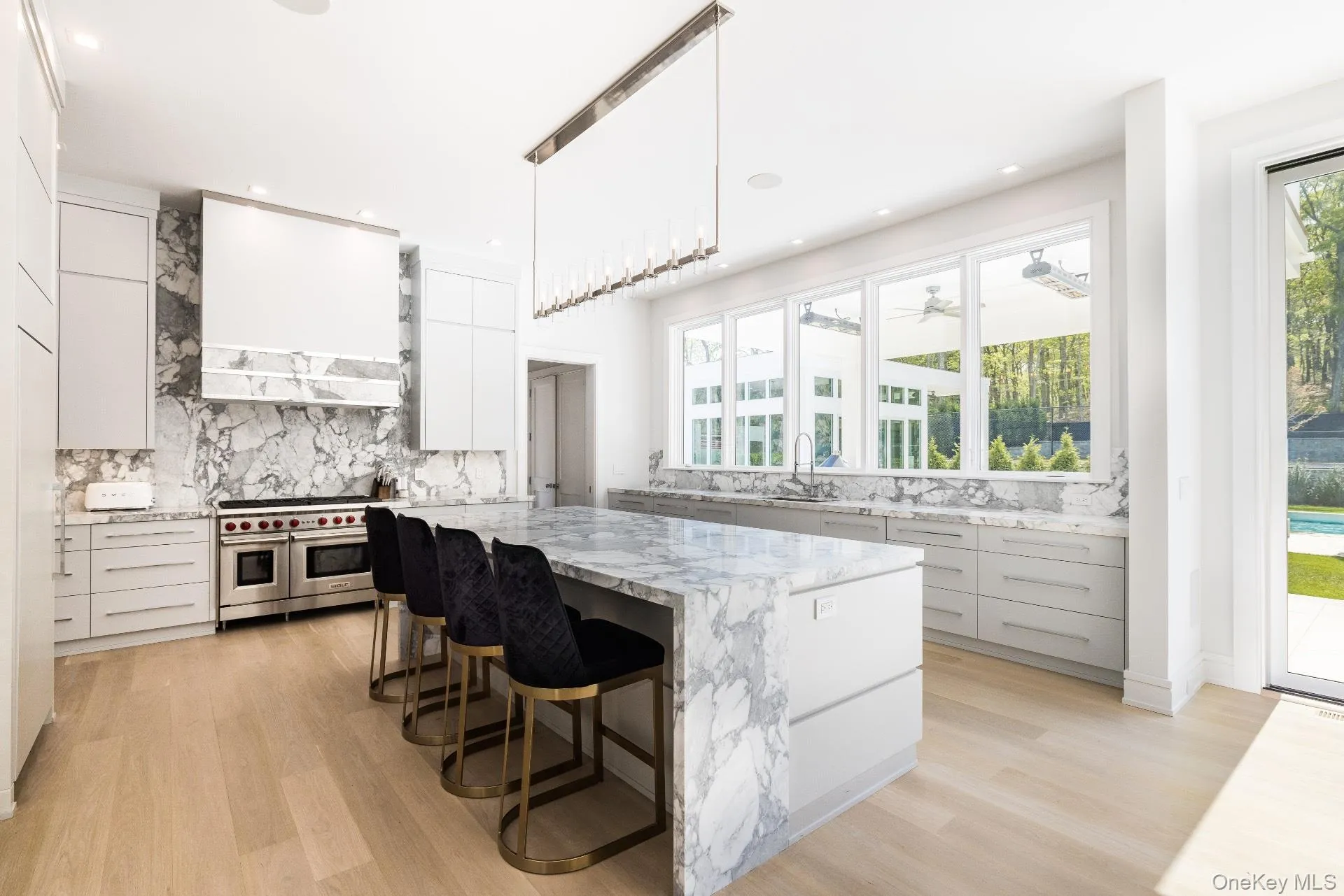 Kitchen featuring light stone countertops, a kitchen breakfast bar, pendant lighting, light wood-style floors, and recessed lighting Kitchen featuring light stone countertops, a kitchen breakfast bar, pendant lighting, light wood-style floors, and recessed lighting
