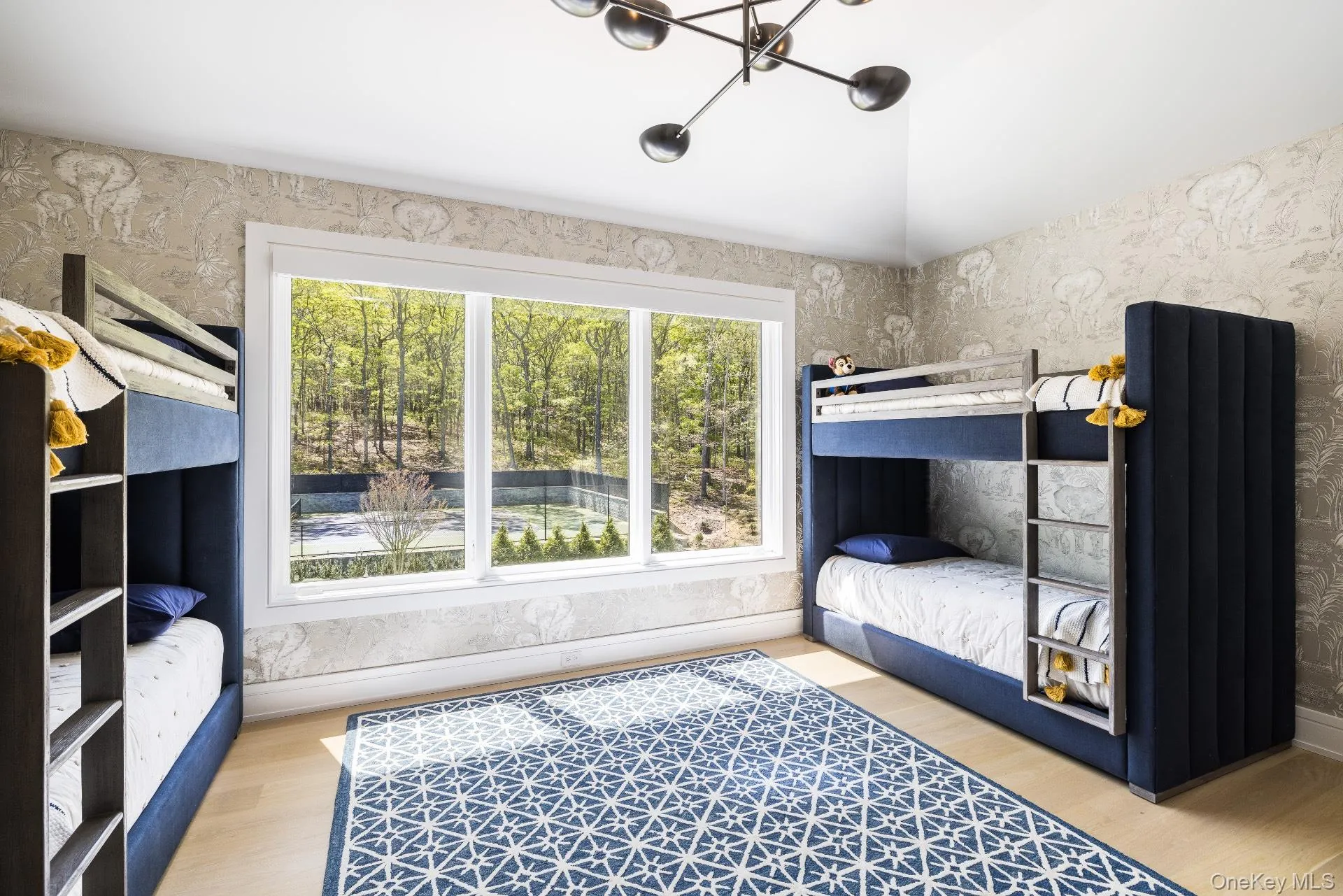 Bedroom with wallpapered walls, light wood finished floors, lofted ceiling, and multiple windows Bedroom with wallpapered walls, light wood finished floors, lofted ceiling, and multiple windows