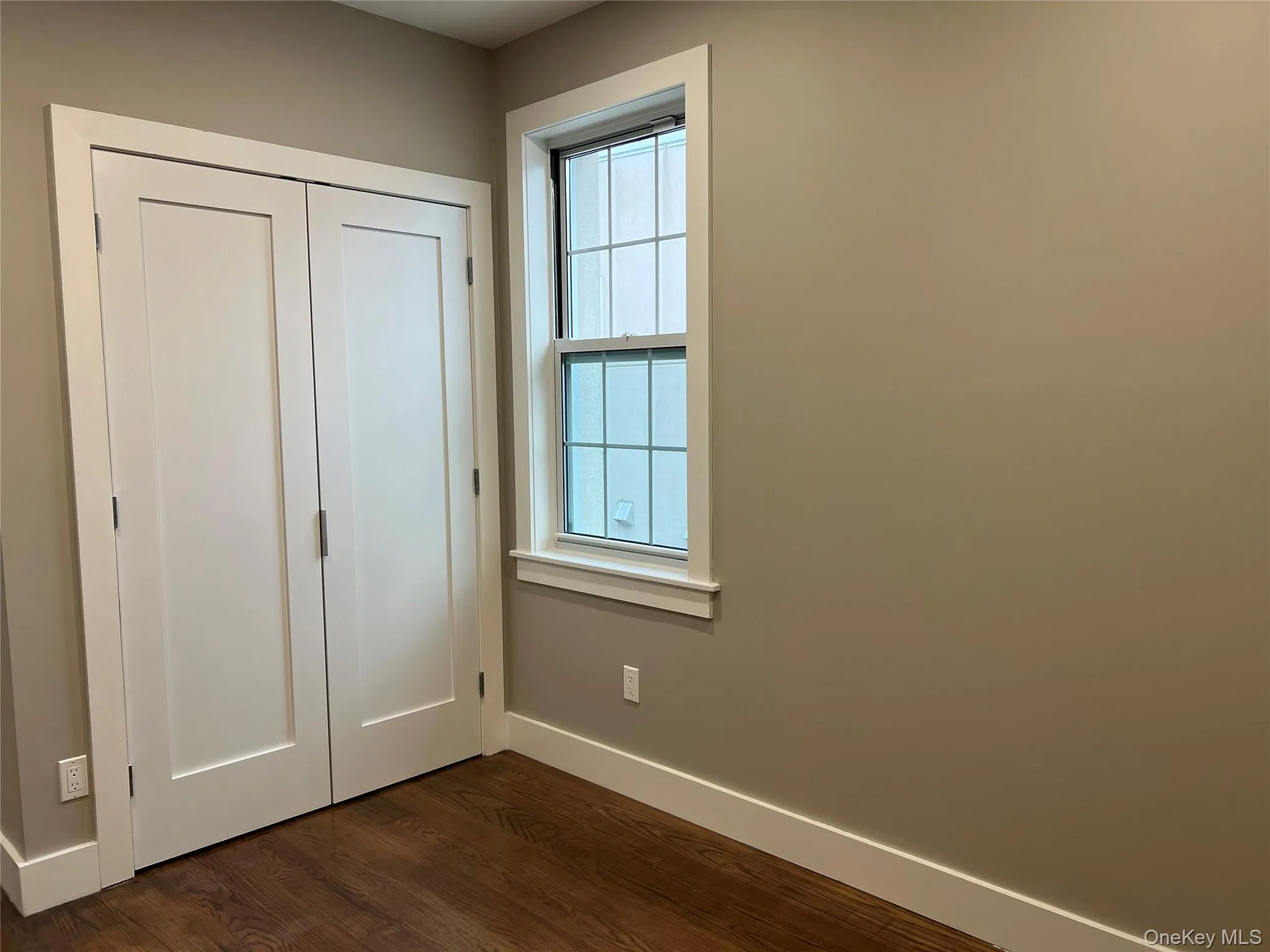Unfurnished bedroom with a closet and dark wood finished floors Unfurnished bedroom with a closet and dark wood finished floors
