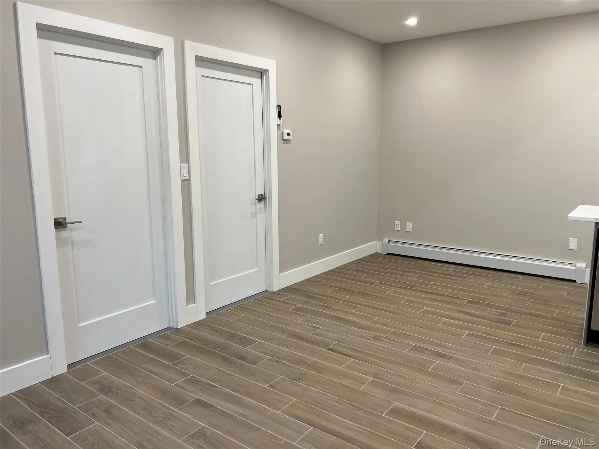 Spare room with wood finish floors, a baseboard heating unit, and recessed lighting Spare room with wood finish floors, a baseboard heating unit, and recessed lighting