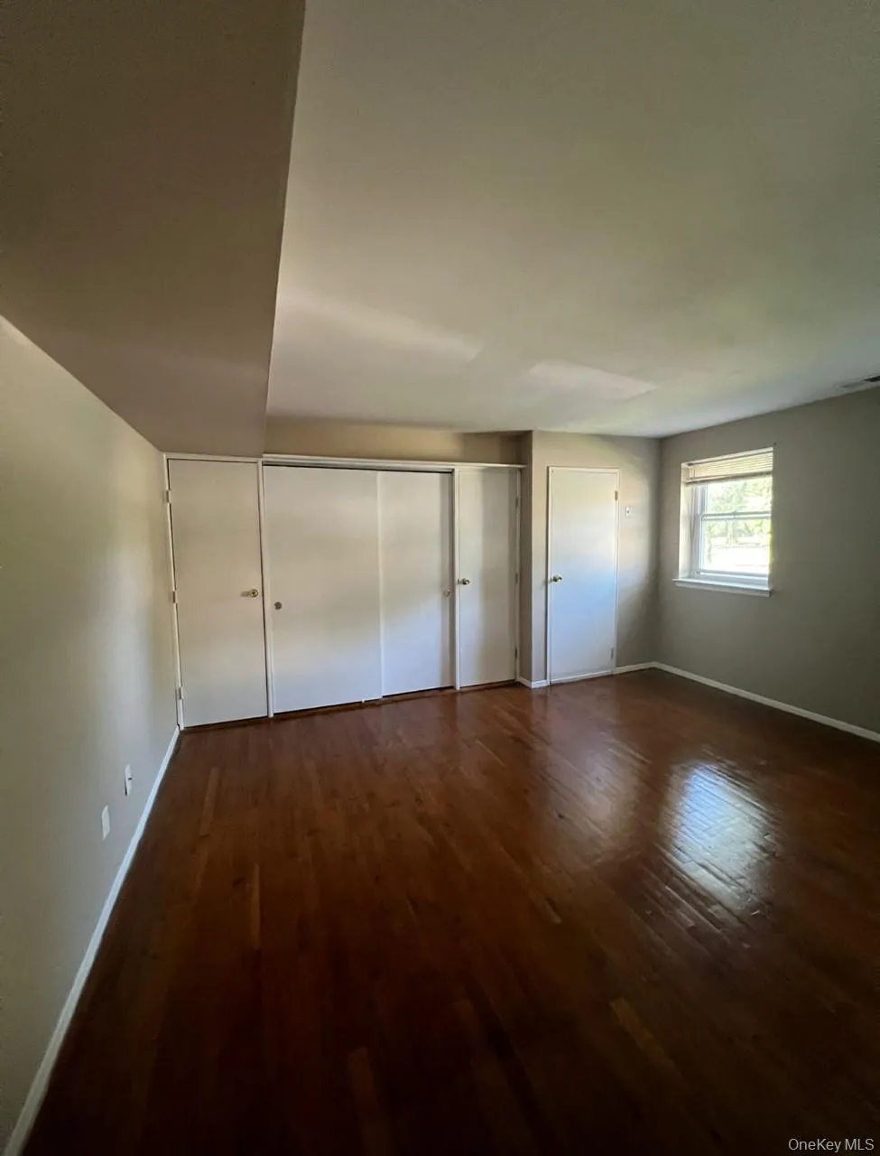 Unfurnished bedroom featuring dark wood-style floors and a closet Unfurnished bedroom featuring dark wood-style floors and a closet