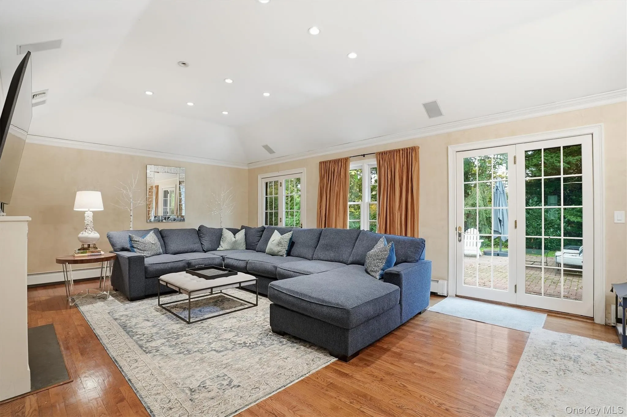 Living room with recessed lighting, light wood-type flooring, and a baseboard heating unit Living room with recessed lighting, light wood-type flooring, and a baseboard heating unit