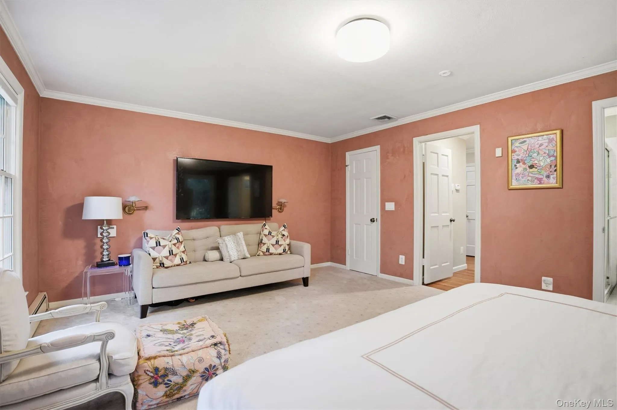 Bedroom with ornamental molding, light carpet, a closet, and baseboard heating Bedroom with ornamental molding, light carpet, a closet, and baseboard heating