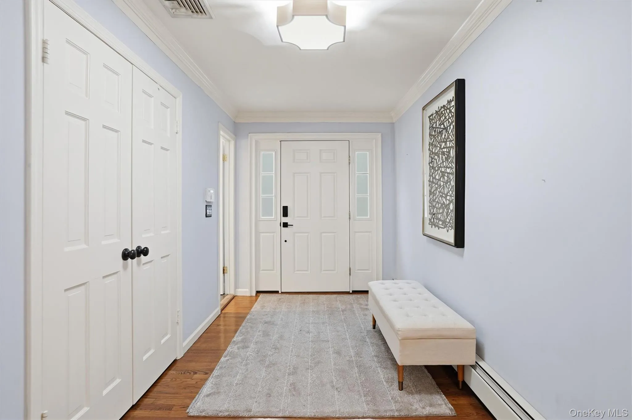 Entryway featuring a baseboard radiator, wood finished floors, and ornamental molding Entryway featuring a baseboard radiator, wood finished floors, and ornamental molding