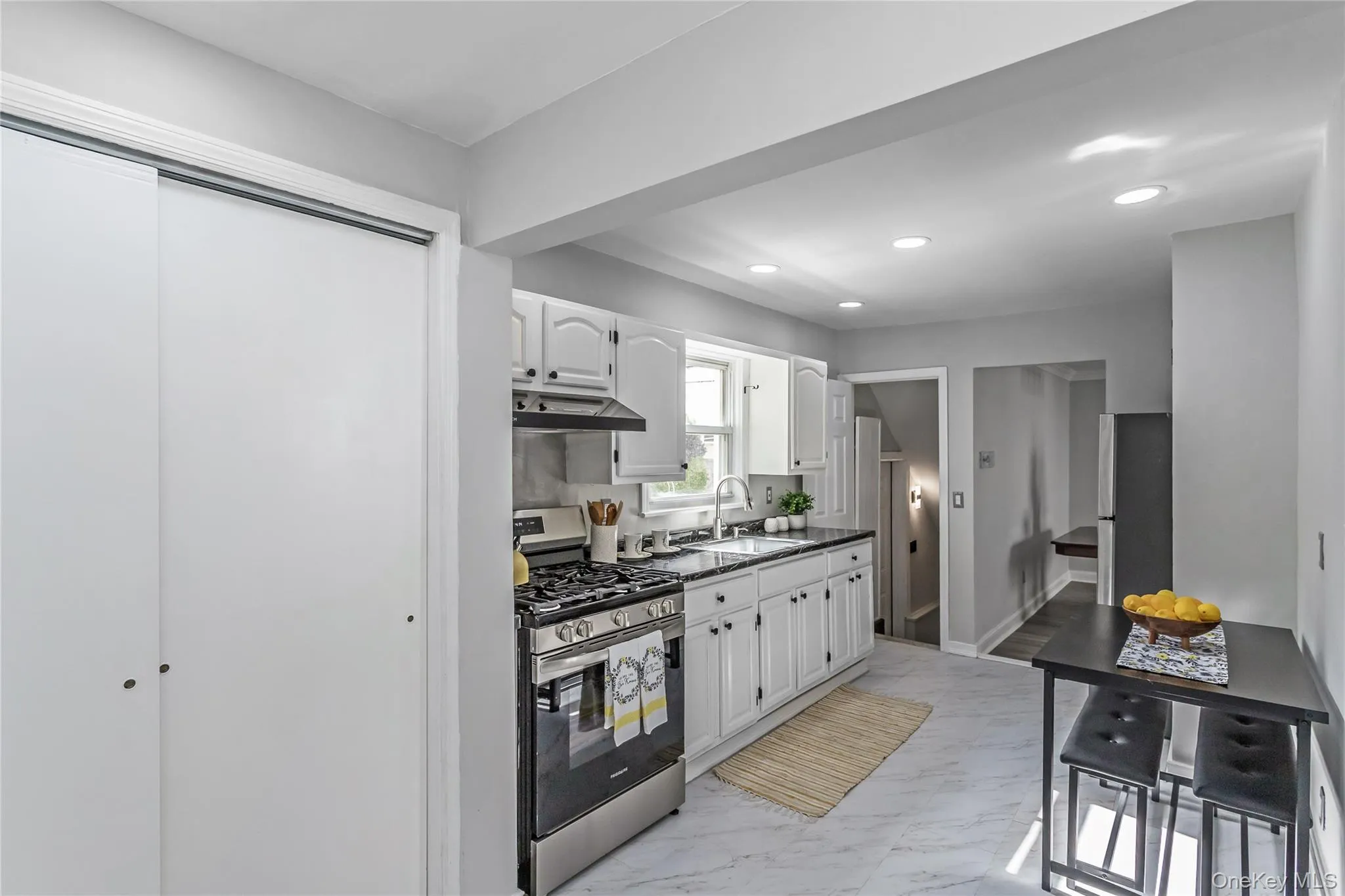 Kitchen featuring appliances with stainless steel finishes, dark countertops, a sink, white cabinets, and under cabinet range hood Kitchen featuring appliances with stainless steel finishes, dark countertops, a sink, white cabinets, and under cabinet range hood