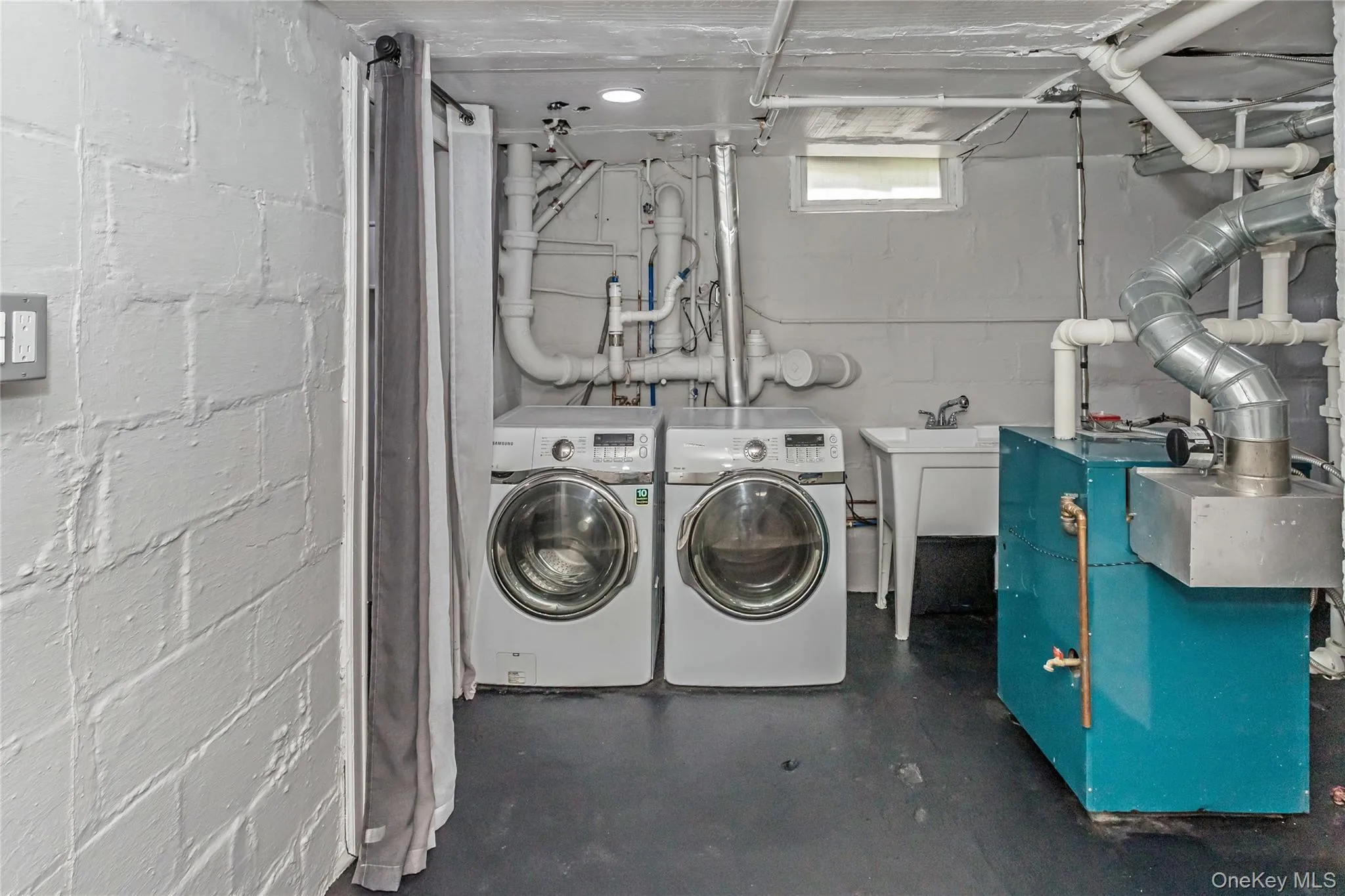Clothes washing area featuring washer and dryer, concrete block wall, laundry area, and a sink Clothes washing area featuring washer and dryer, concrete block wall, laundry area, and a sink