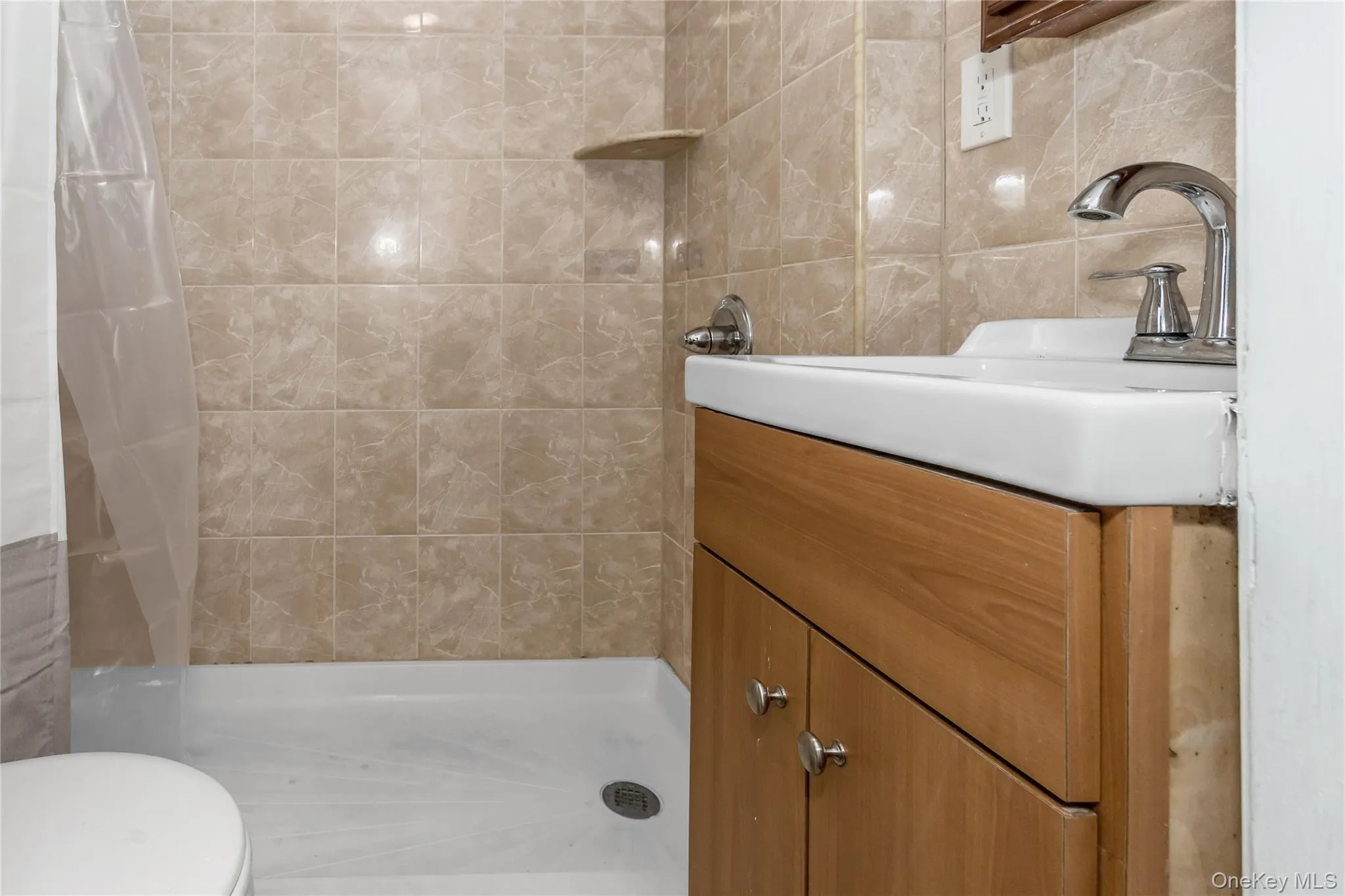 Bathroom featuring toilet, tile walls, tiled shower, and vanity Bathroom featuring toilet, tile walls, tiled shower, and vanity