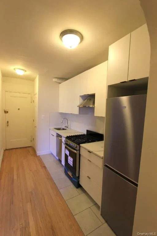 Kitchen with appliances with stainless steel finishes, white cabinetry, and modern cabinets Kitchen with appliances with stainless steel finishes, white cabinetry, and modern cabinets